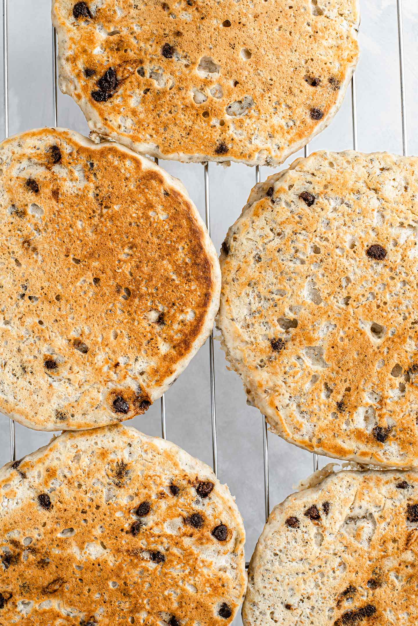 Cooked chia chip pancakes cool on a wire rack. They are golden brown and the chips are melty.