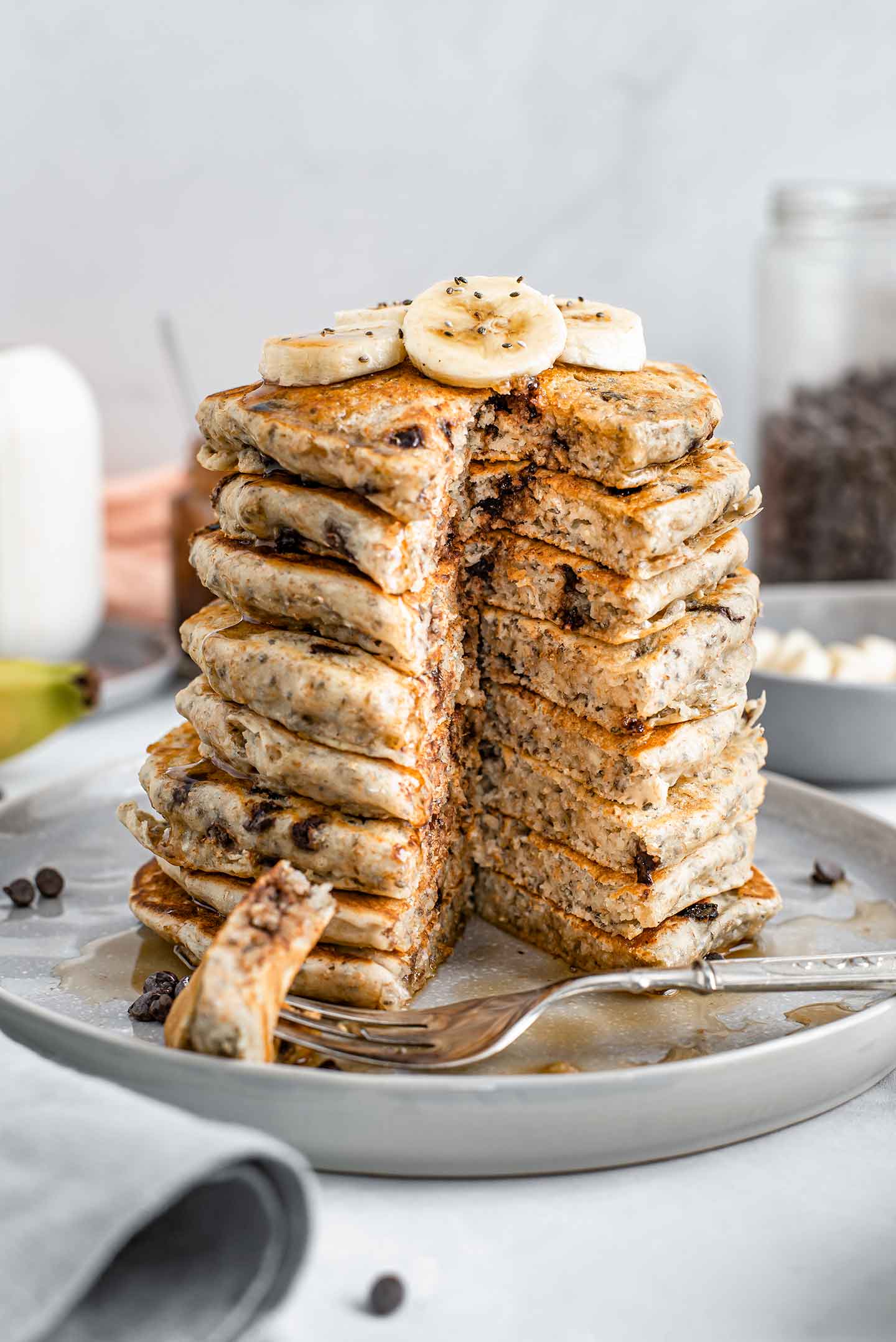 Side view of a tower of pancakes with a triangle cut through all of them. The fluffy, chocolate chip and chia filled insides are visible.