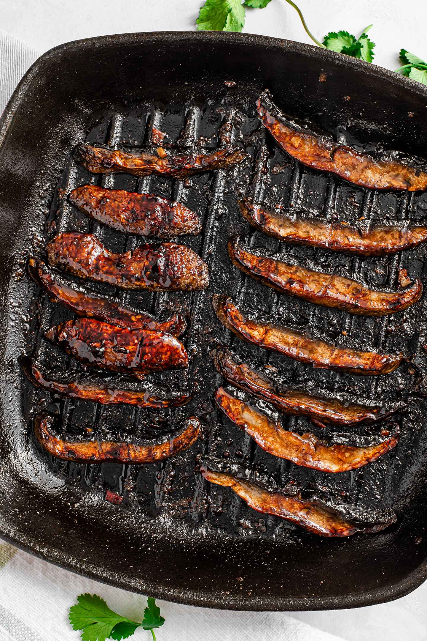 Top down view of dark, grilled mushroom strips in a grill pan.