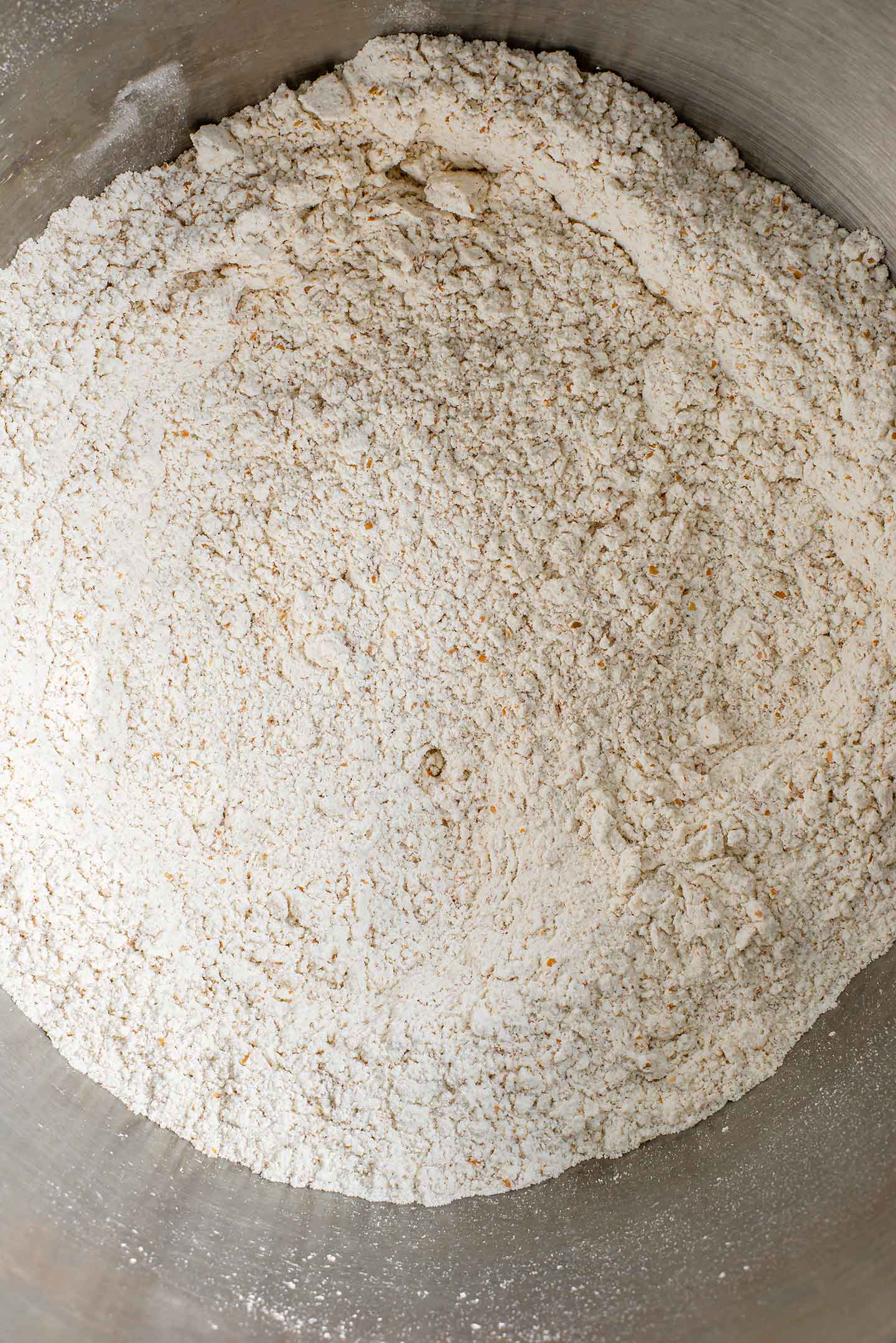 Top down view of whole wheat, white flour, and salt combined in a mixing bowl.