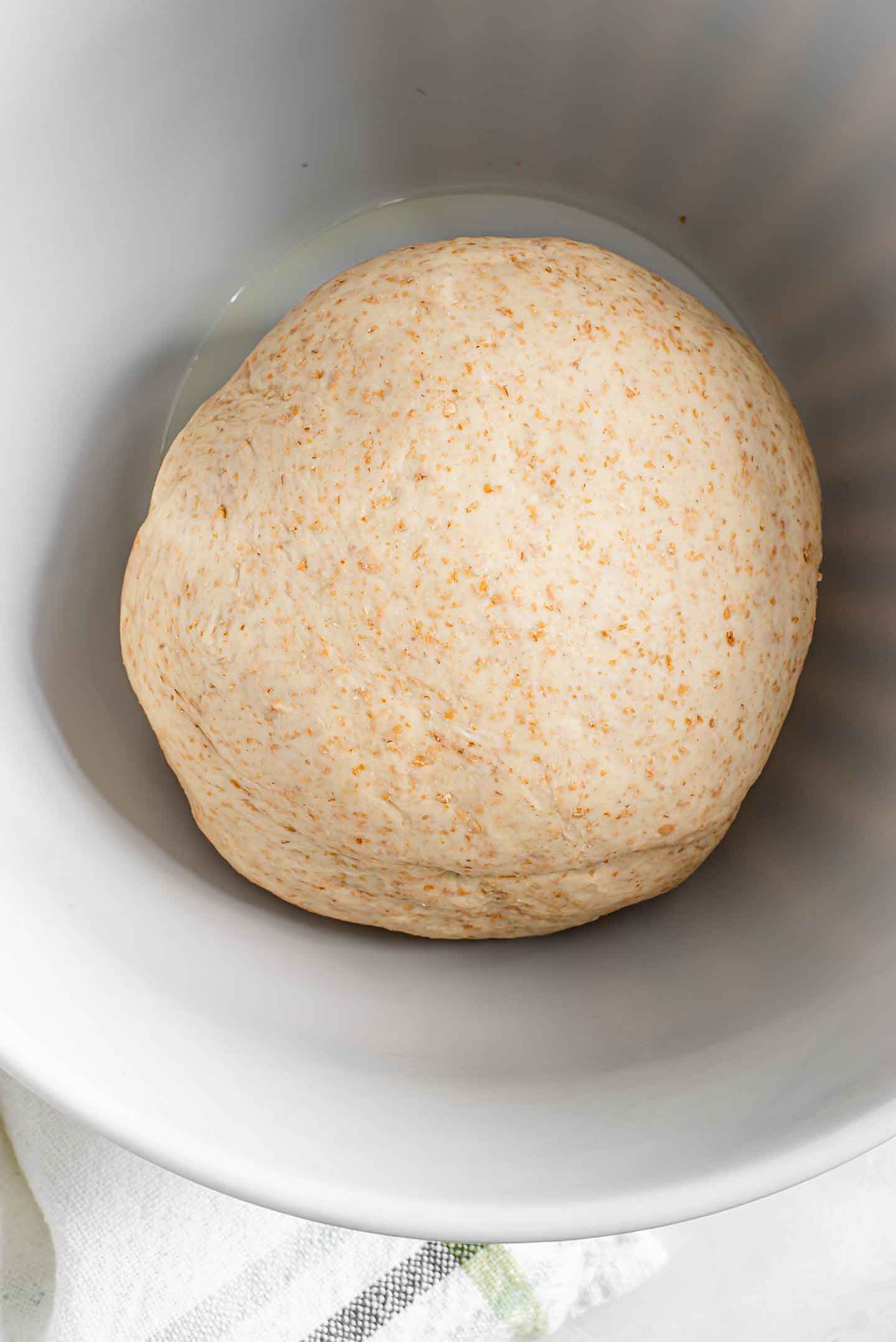 Top down view of a formed ball of our easy pizza dough recipe in a lightly oiled bowl.