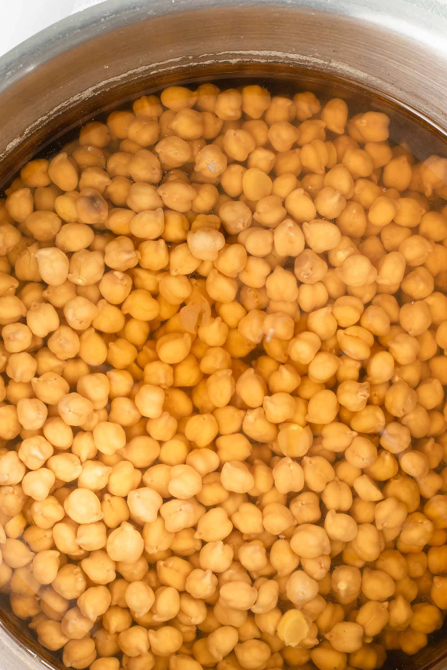 Top down view of soaked chickpeas in a large pot of water.