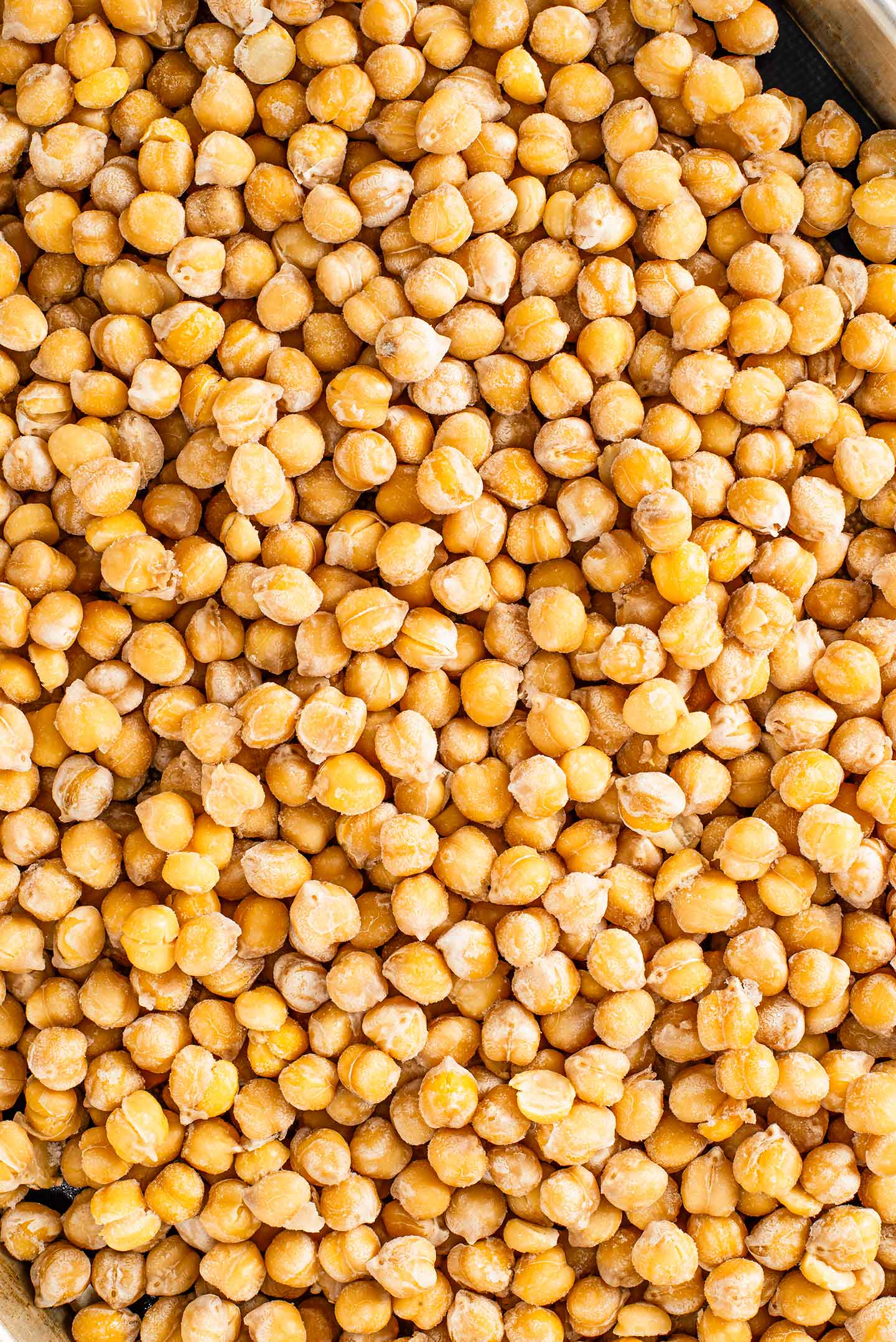 Top down view of frozen chickpeas spread on a baking sheet.