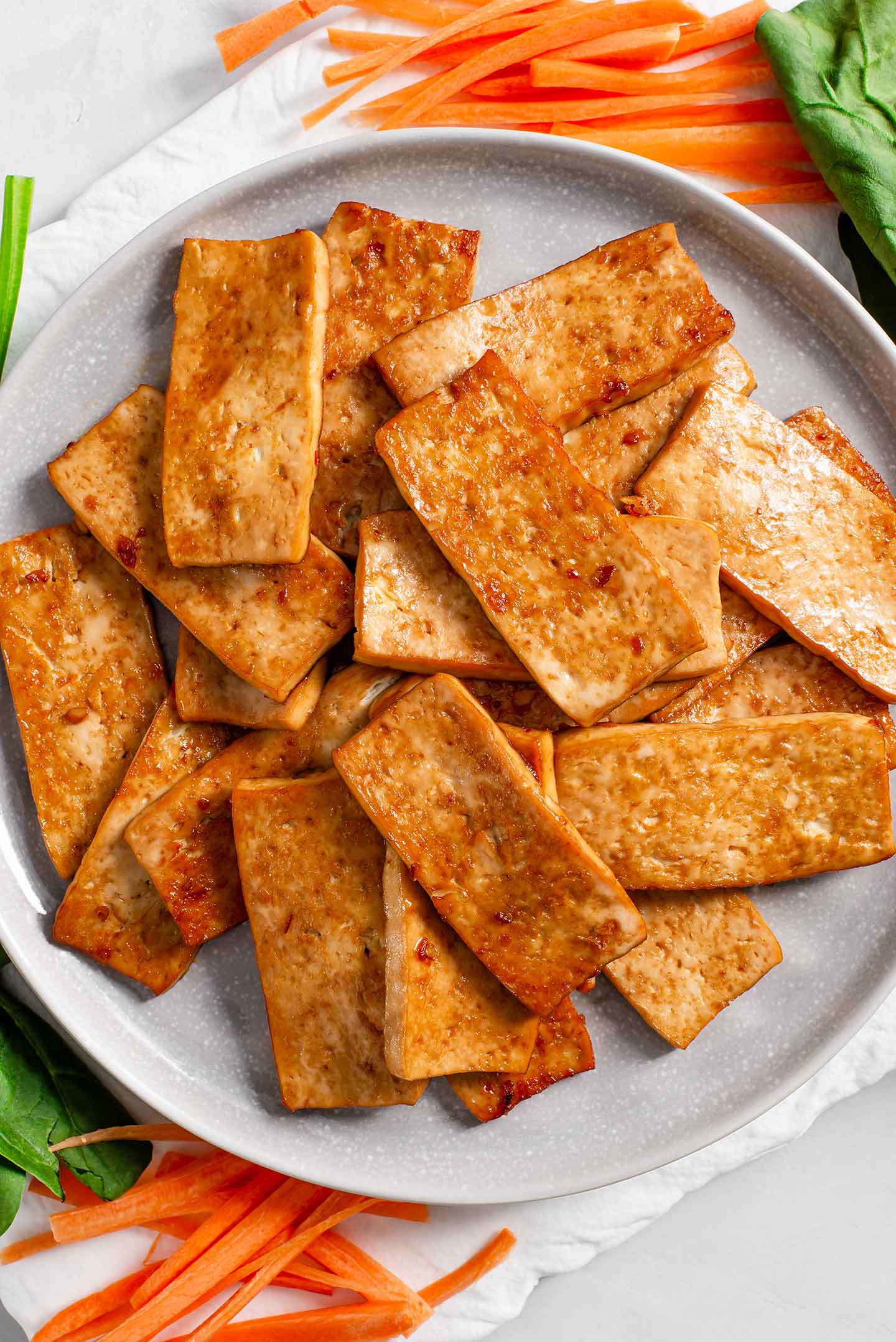 Top down view of cooked and seasoned strips of tofu. They are golden and crispy.