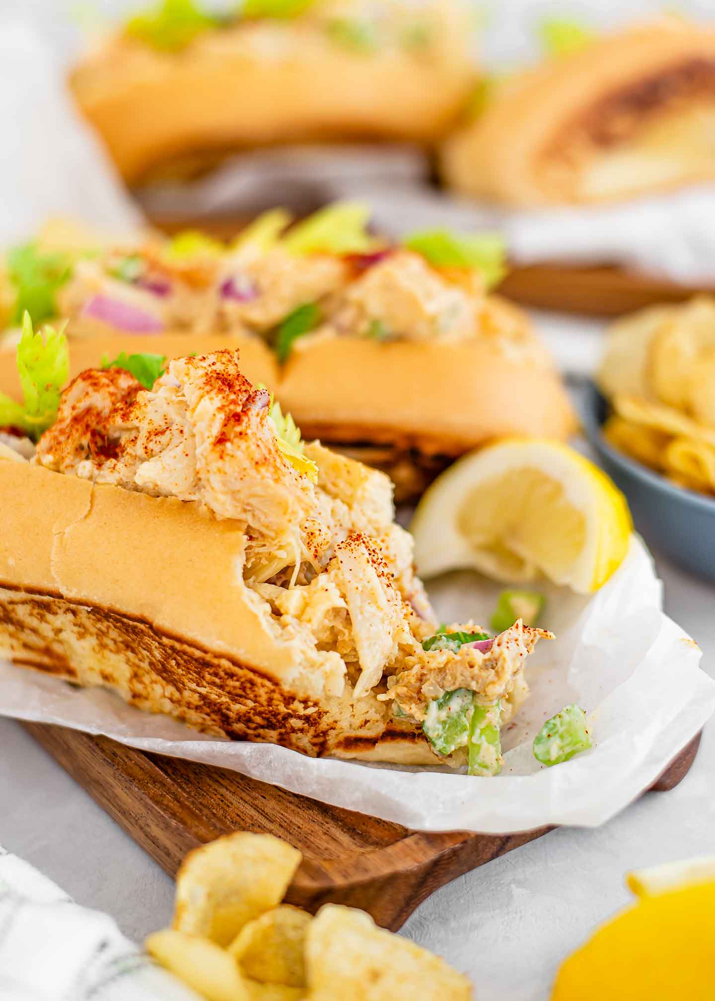 Side view of a large bite missing from a lobster roll. The fish-less meat spills out of the buttery roll showing the tasty creation.