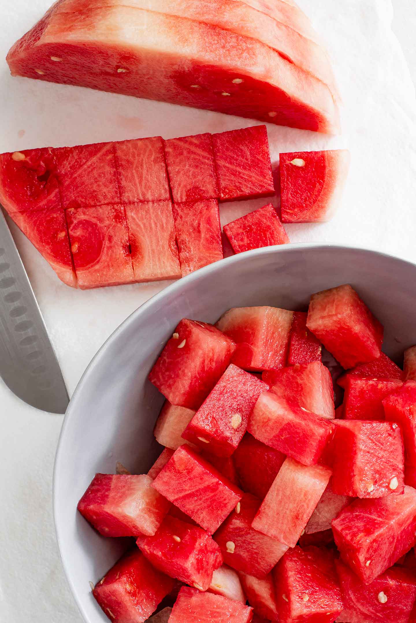 Top down view of a peeled watermelon being cubed into poke.