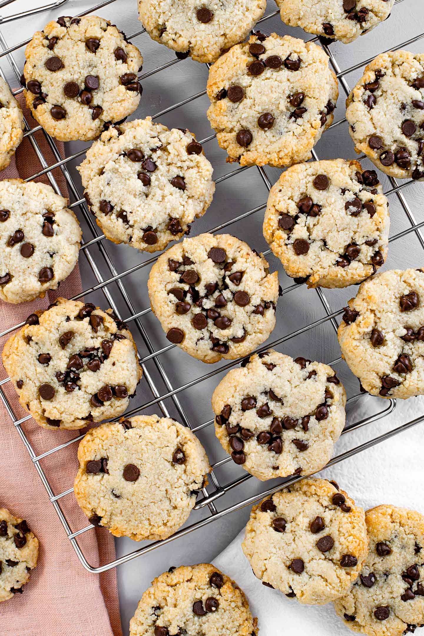 Top down view of fresh baked cookies on a drying rack, loaded with chocolate chips and golden around the edges.