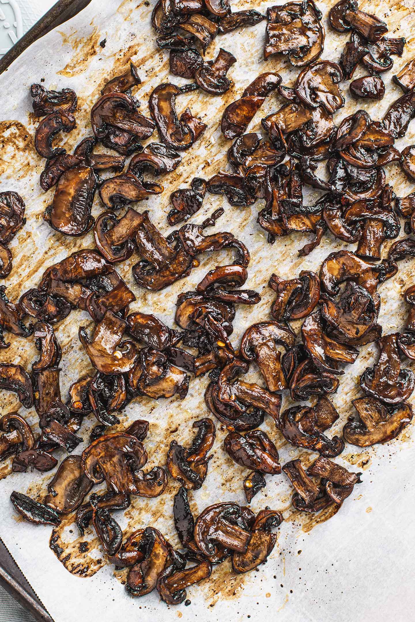 Top down view of cooked smoky spicy mushrooms on a baking sheet lined with parchment paper.