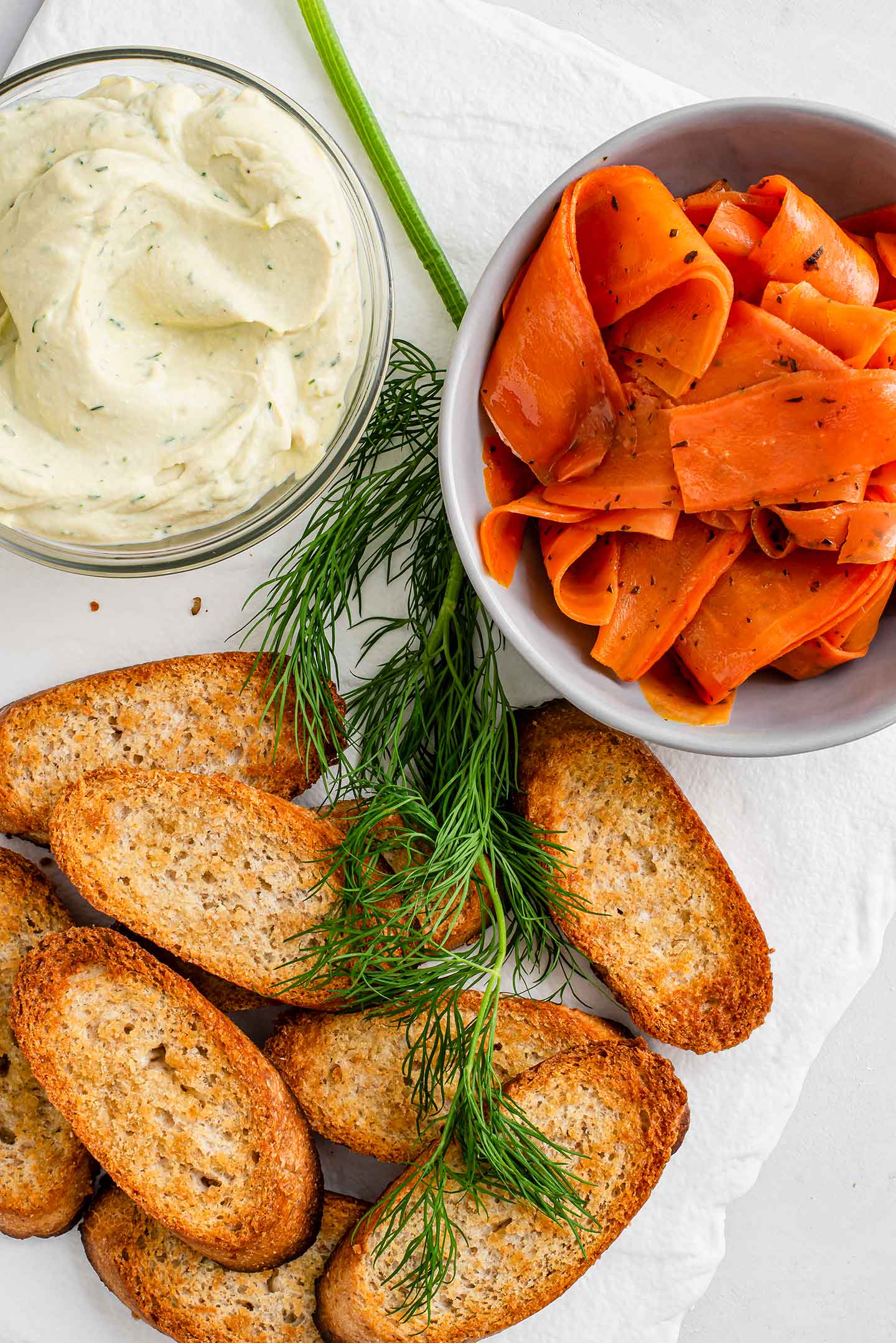 Top down view of toasted crostini, carrot lox, and creamy dill spread for the smoky carrot lox appetizer.