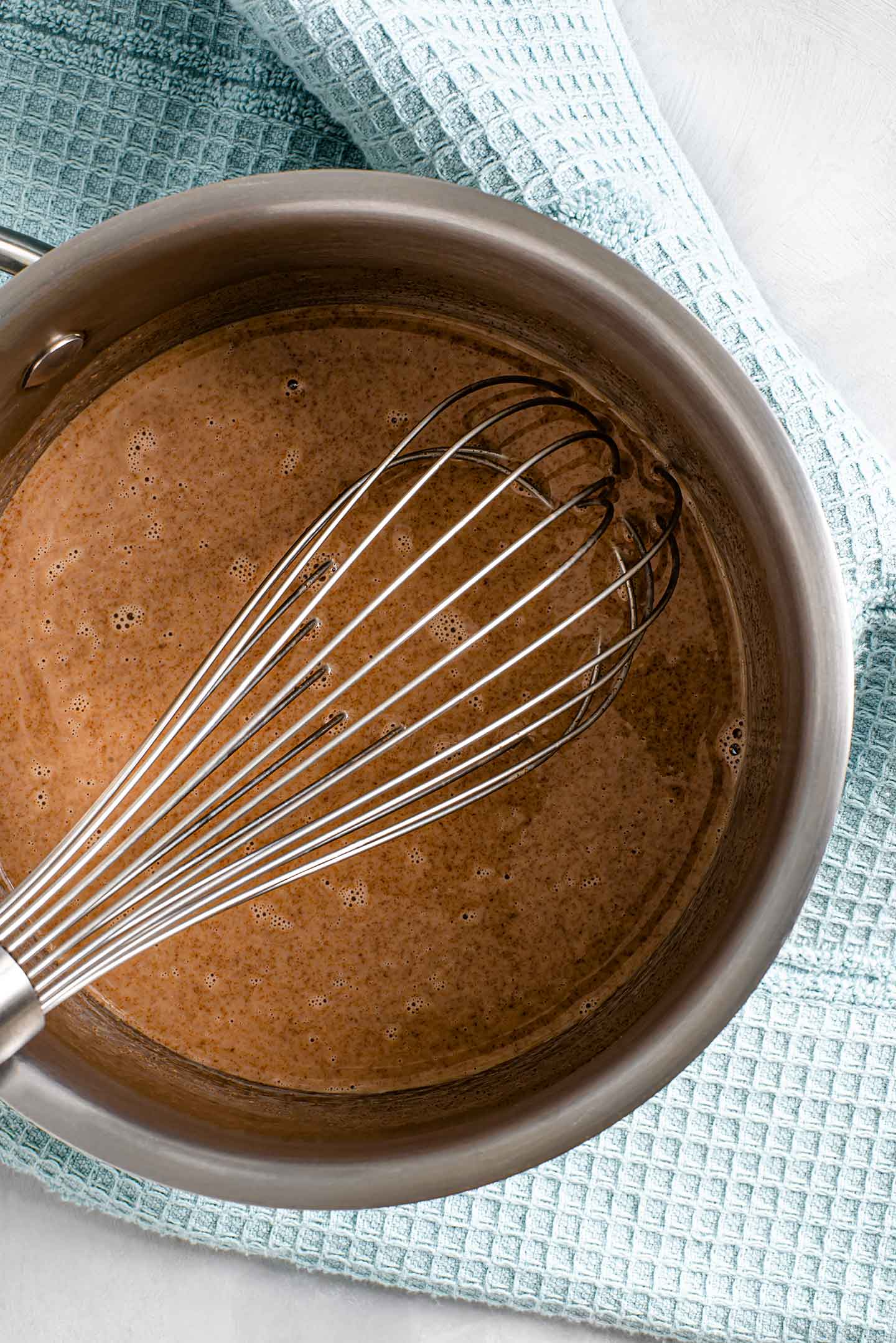 Top down view of chocolate milk being whisked in a small pot.