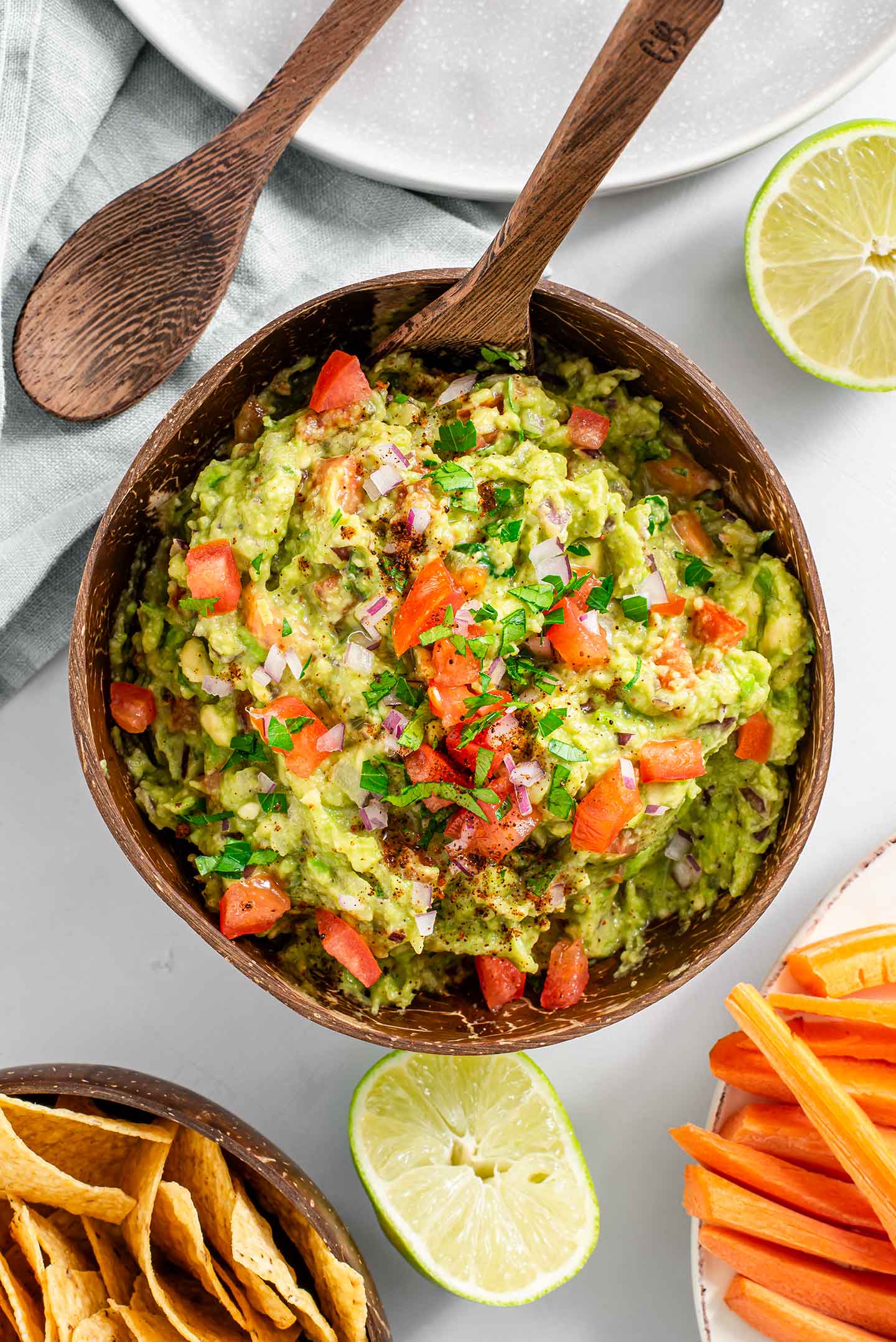 Top down view of timely guacamole filling a 500 gram coconut bowl with tomato, red onion, and cilantro sprinkled on top.