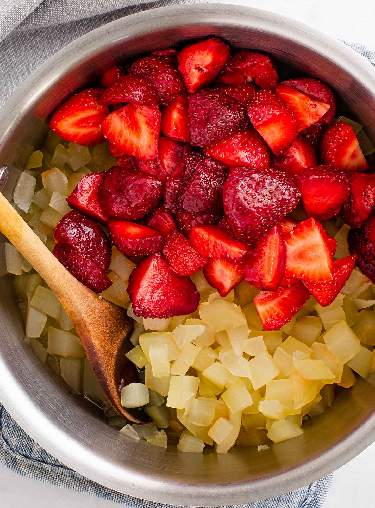 Top down view of diced strawberries being added to the pot. 