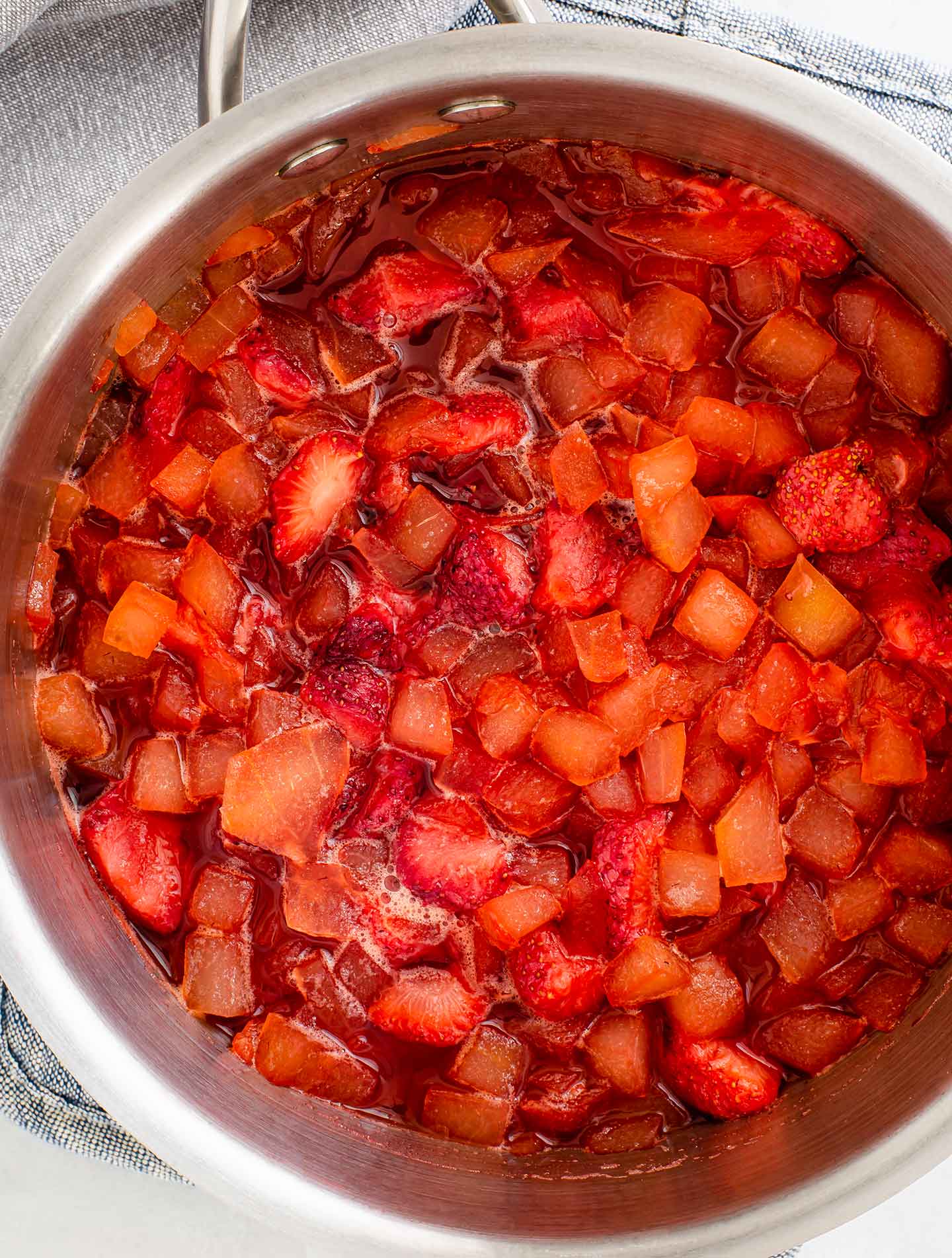 Top down view of watermelon rind and strawberries that are soft and mushy in a pot.