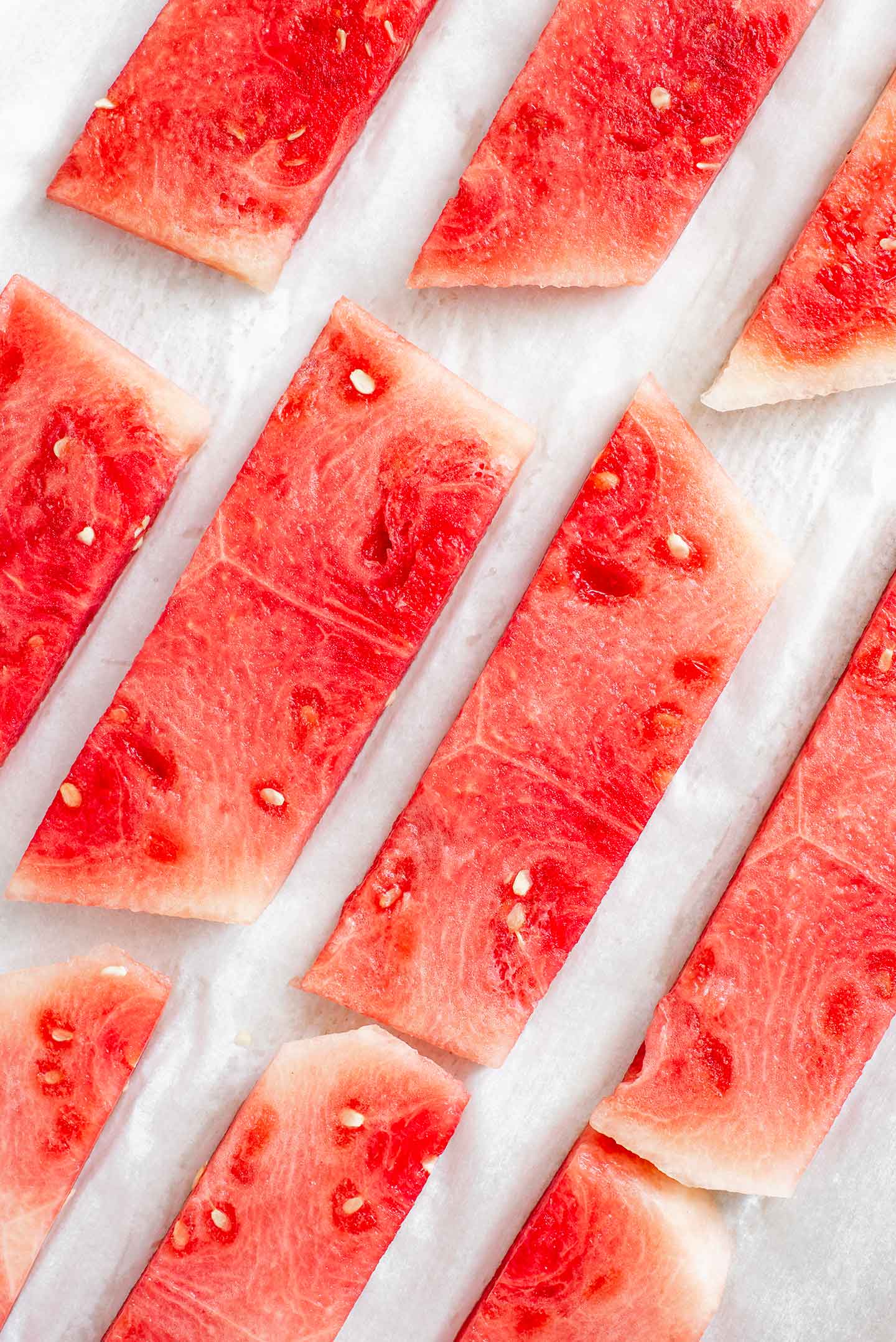 Top down view of rectangular slices of watermelon on a baking sheet.