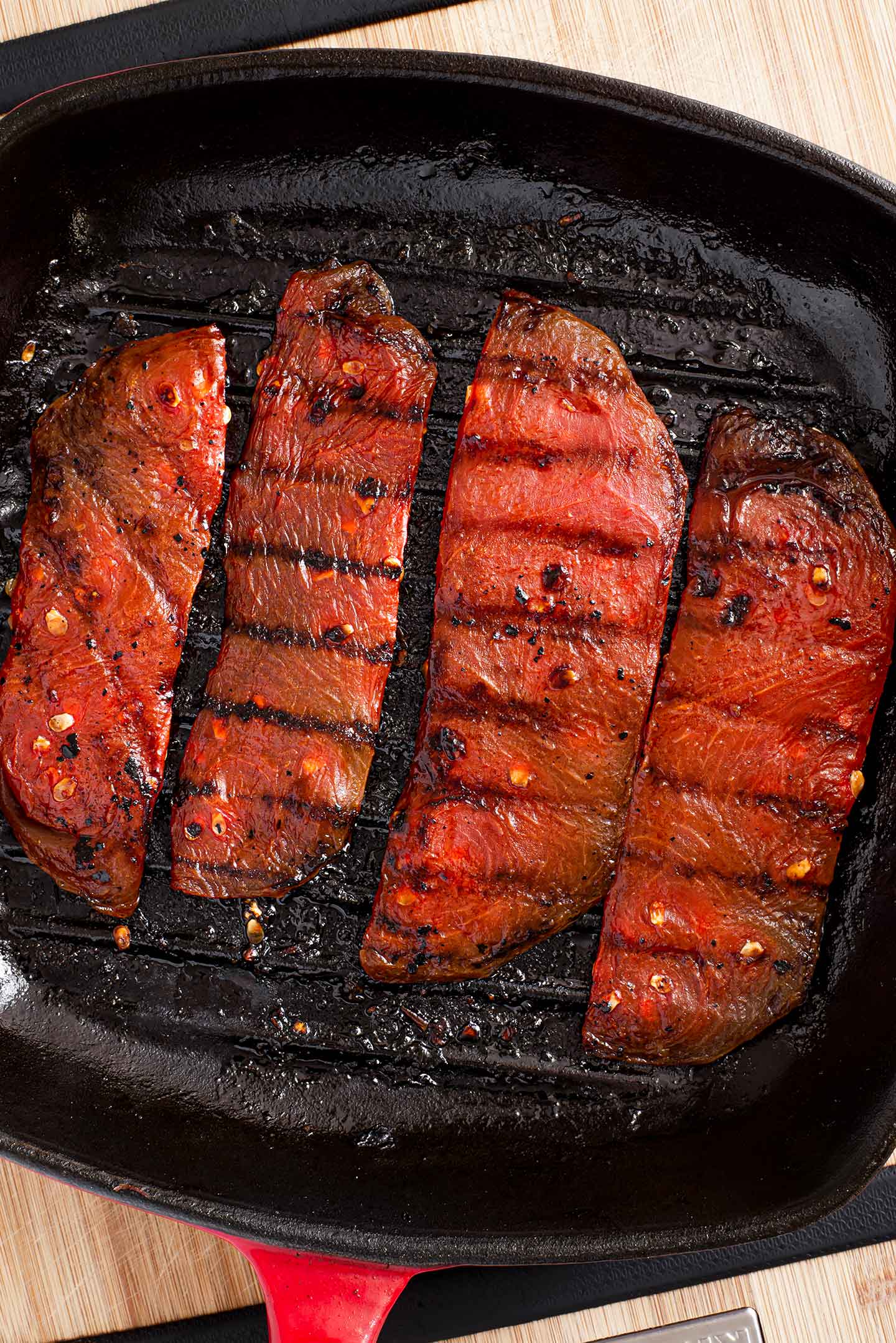 Top down view of watermelon steaks on a hot grill with grill lines seared into the fruit.