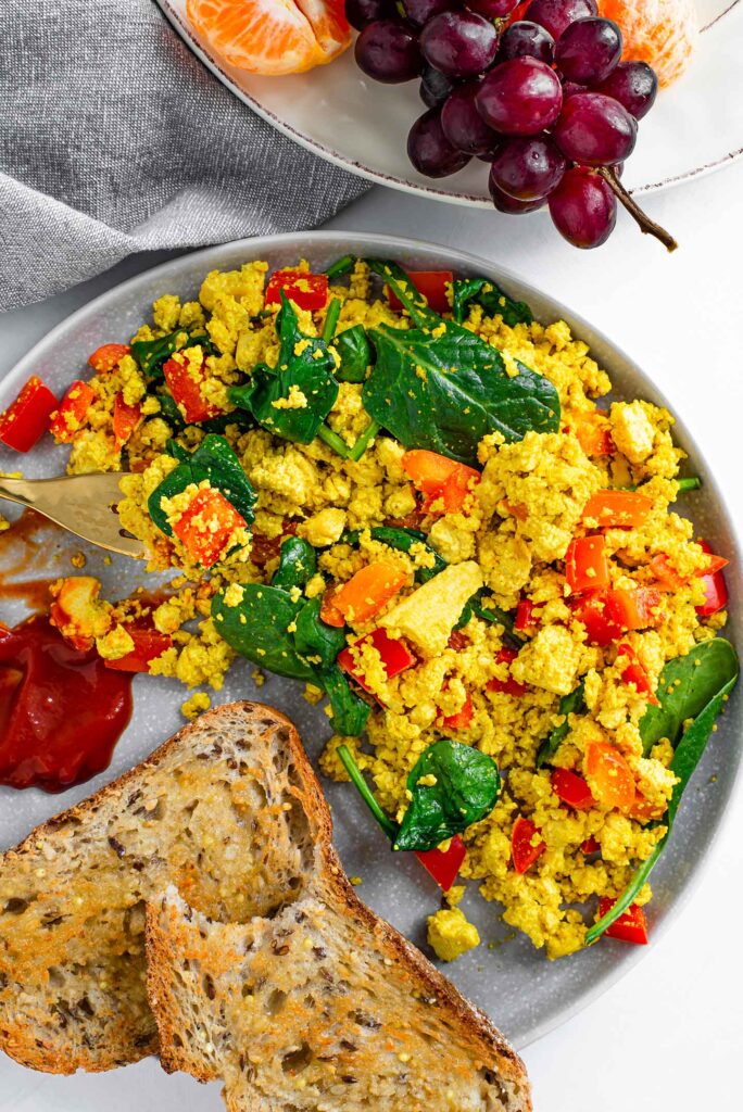 Top down view of 10 minute breakfast scramble on a plate with slices of toast, a squirt of ketchup and a fork digging in.