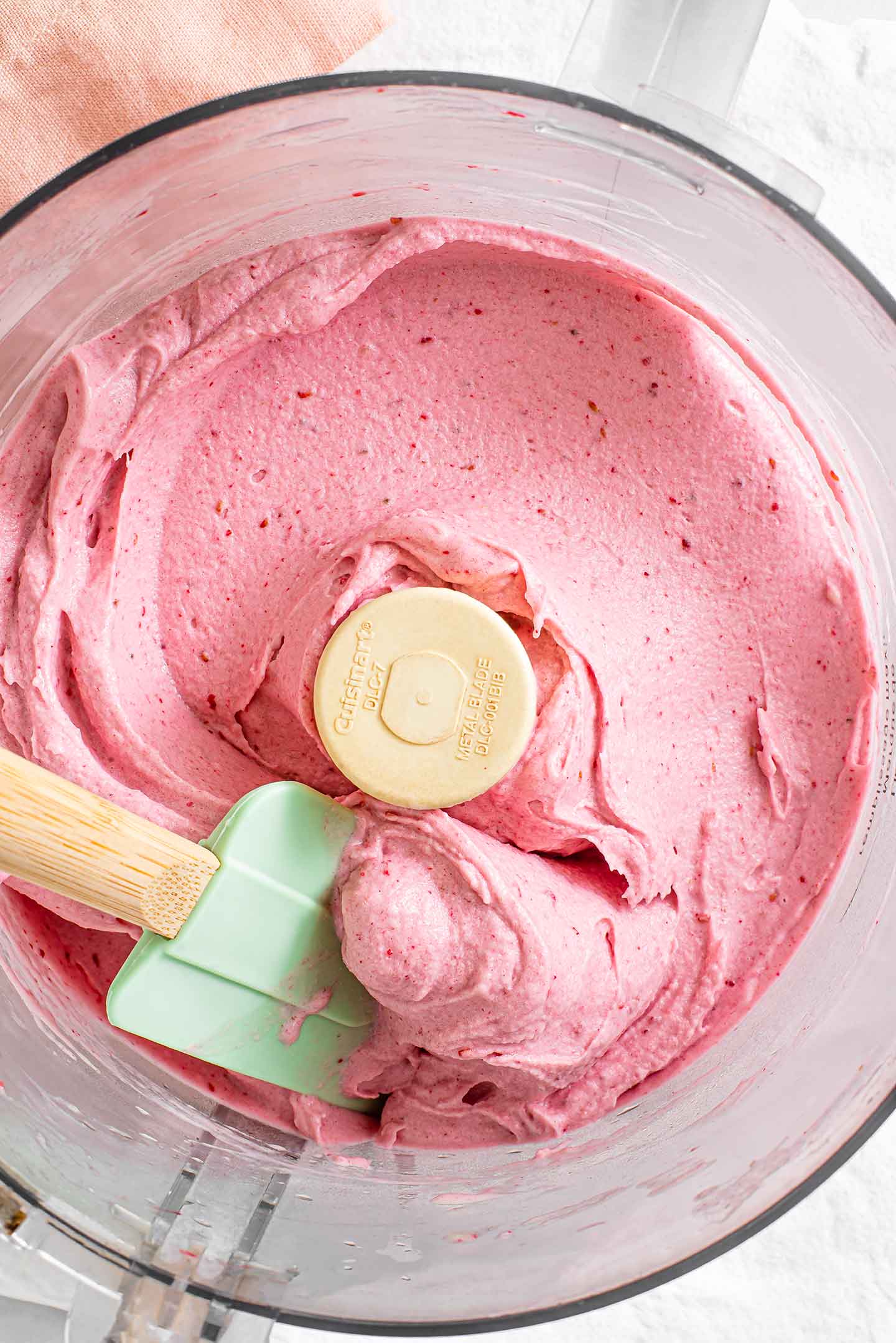 Top down view of bright pink blended raspberry nice cream in a food processor.