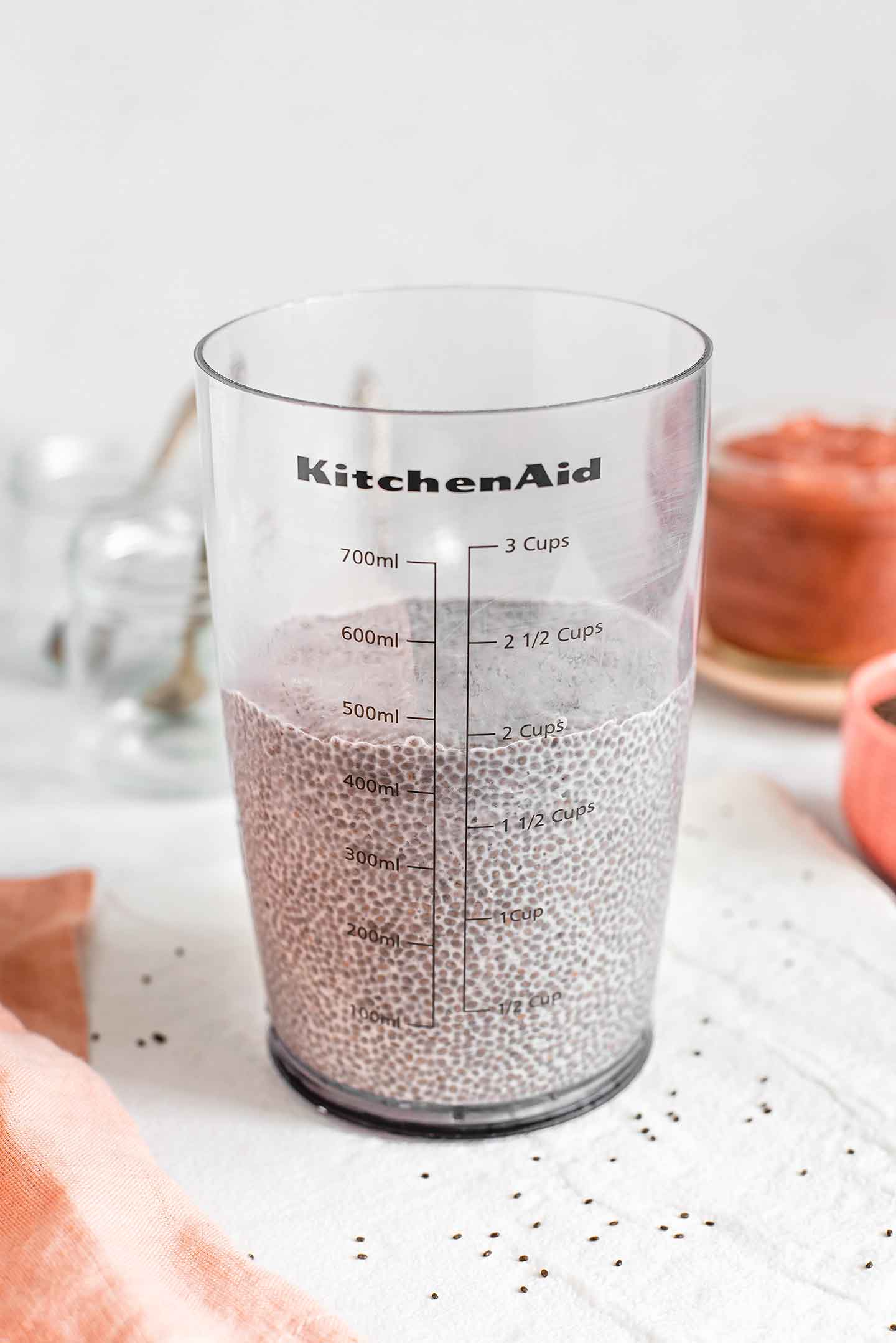 Side view of set and thickened chia pudding in a see through container with measurements. The pudding reaches the 2 cups line.