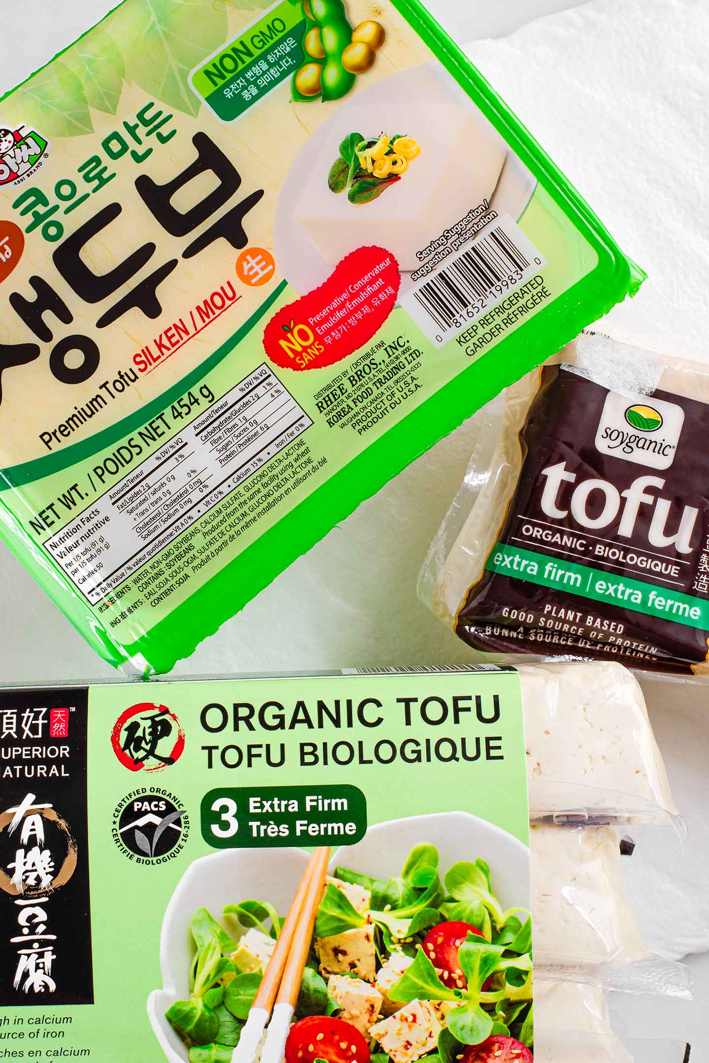 Top down view of two varieties of packaged extra firm tofu and one package of silken tofu.