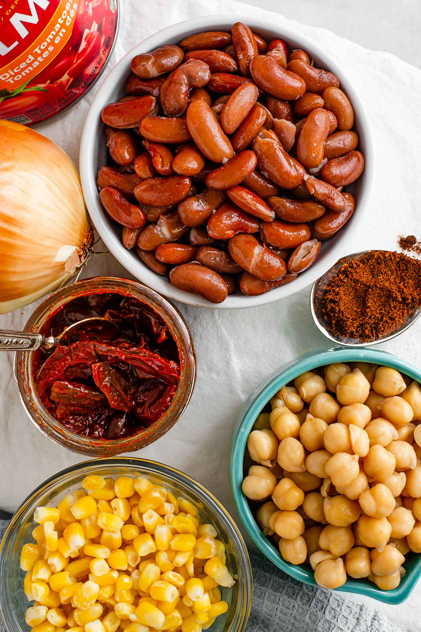 Top down view of an assortment of beans and seasonings on a white tray.