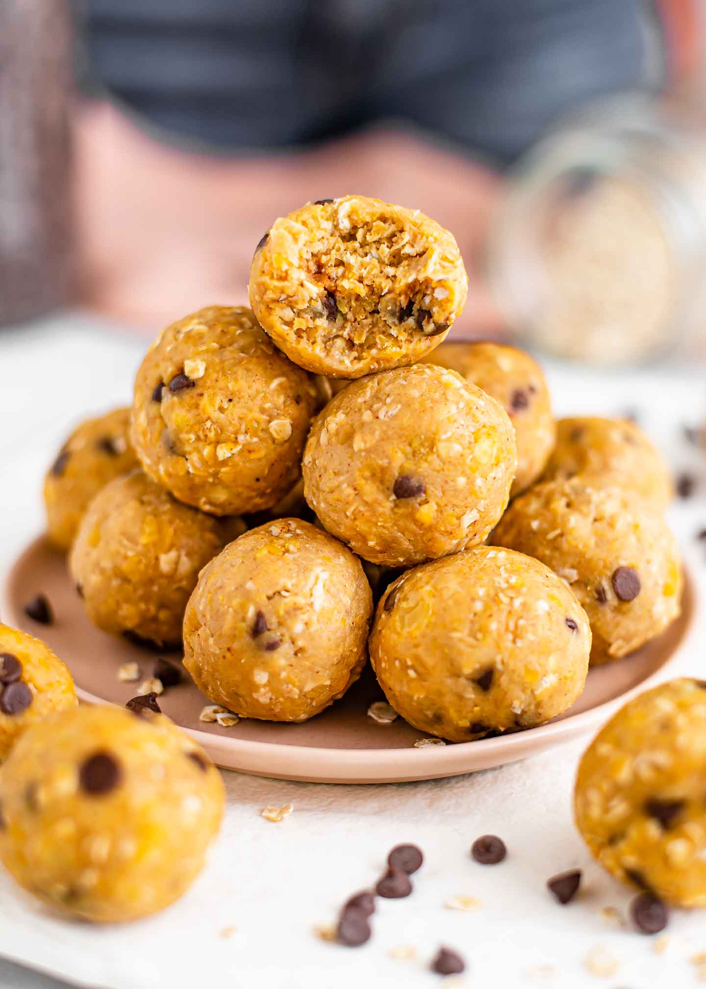 Side view of a stack of protein balls. A bite is missing from the top ball exposing the soft interior speckled with chocolate chips. 