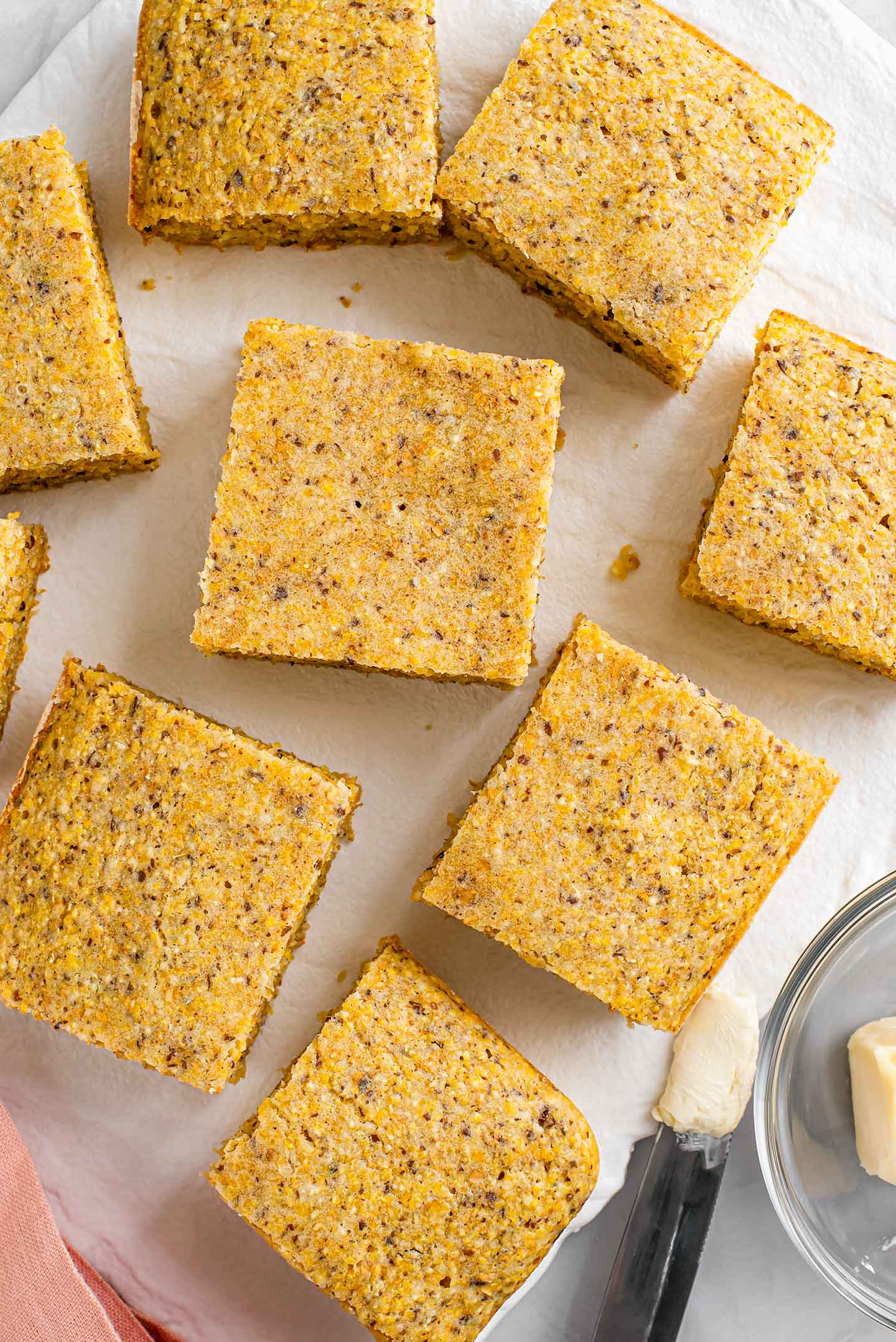 Top down view of kid approved cornbread sliced into squares on a white tray. The cornbread is golden, speckled, fluffy and crispy around the edges.