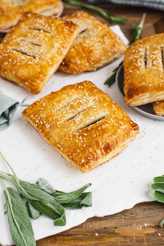 Top down view of golden puff pastry pockets. The pastries are quite large with three slits in the top exposing the spinach, mushroom, tofu filling.
