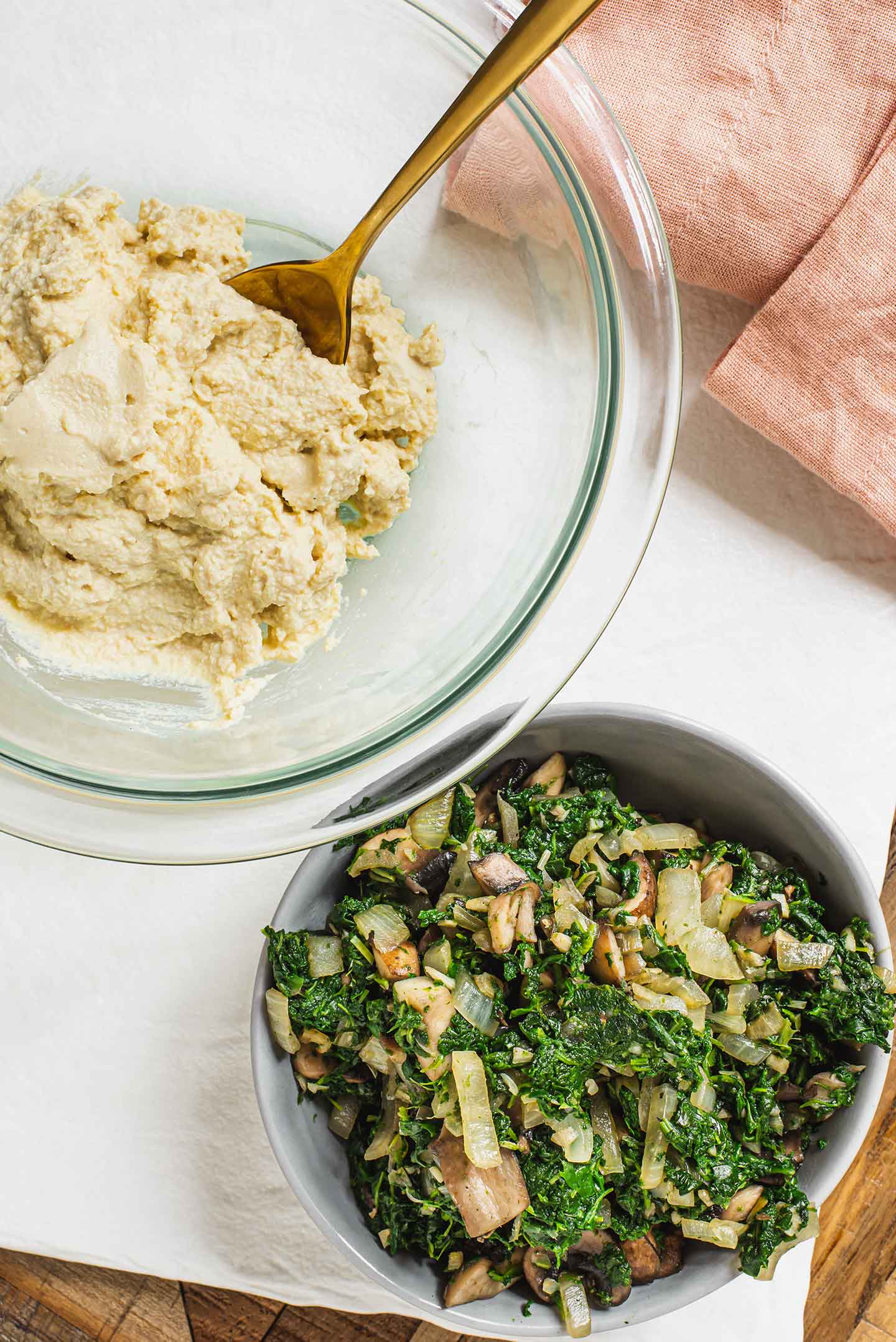 Top down view of the cooked spinach and mushroom mixture beside a bowl of creamy and textured tofu ricotta.
