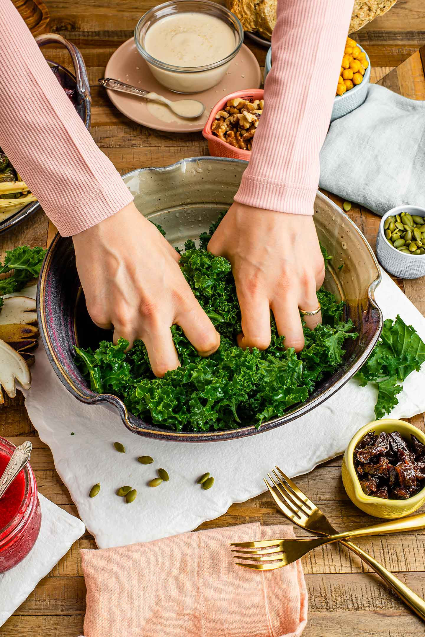 Top down view of two hands massaging a salad bowl full of kale.