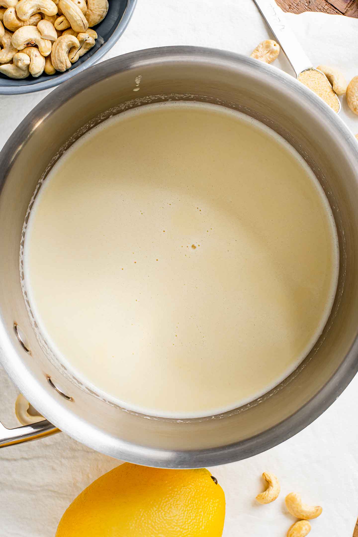 Top down view of a thin blended white sauce in a metal pot.