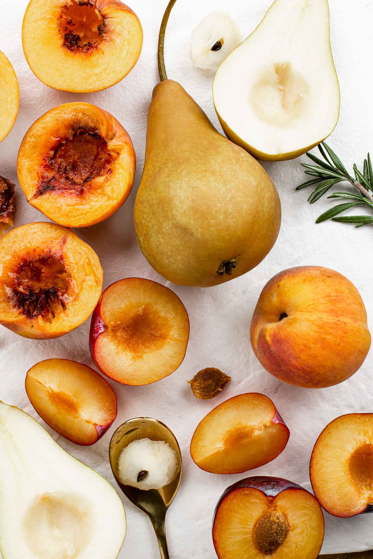 Top down view of pears, peaches, and plums partially sliced and cored or de-stoned.