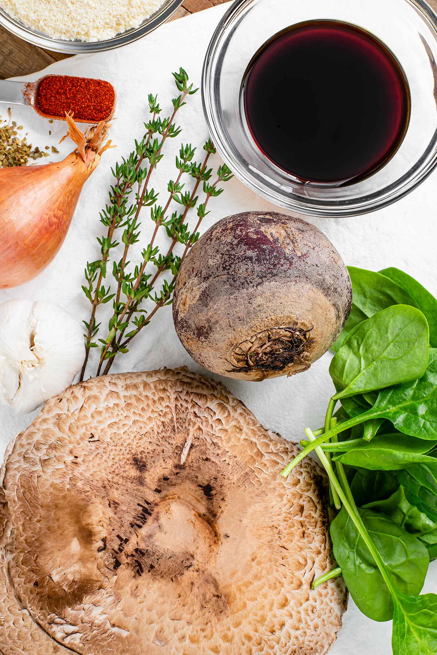 Top down view of ingredients for an easy vegan beet wellington. Beet, mushroom, spinach, amount seasonigns and herbs.