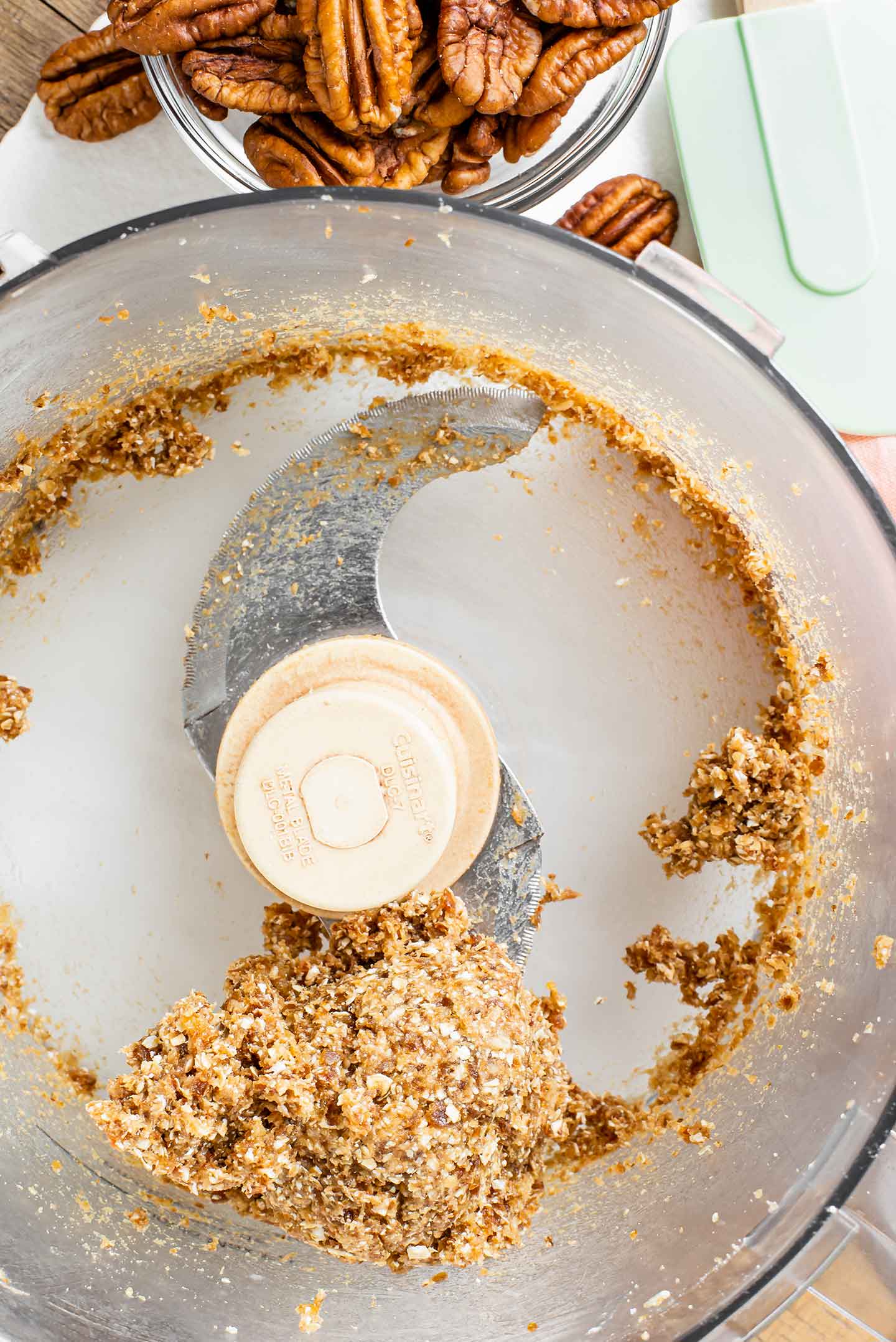 Top down view of the date caramel forming a sticky dough in the bowl of a food processor.