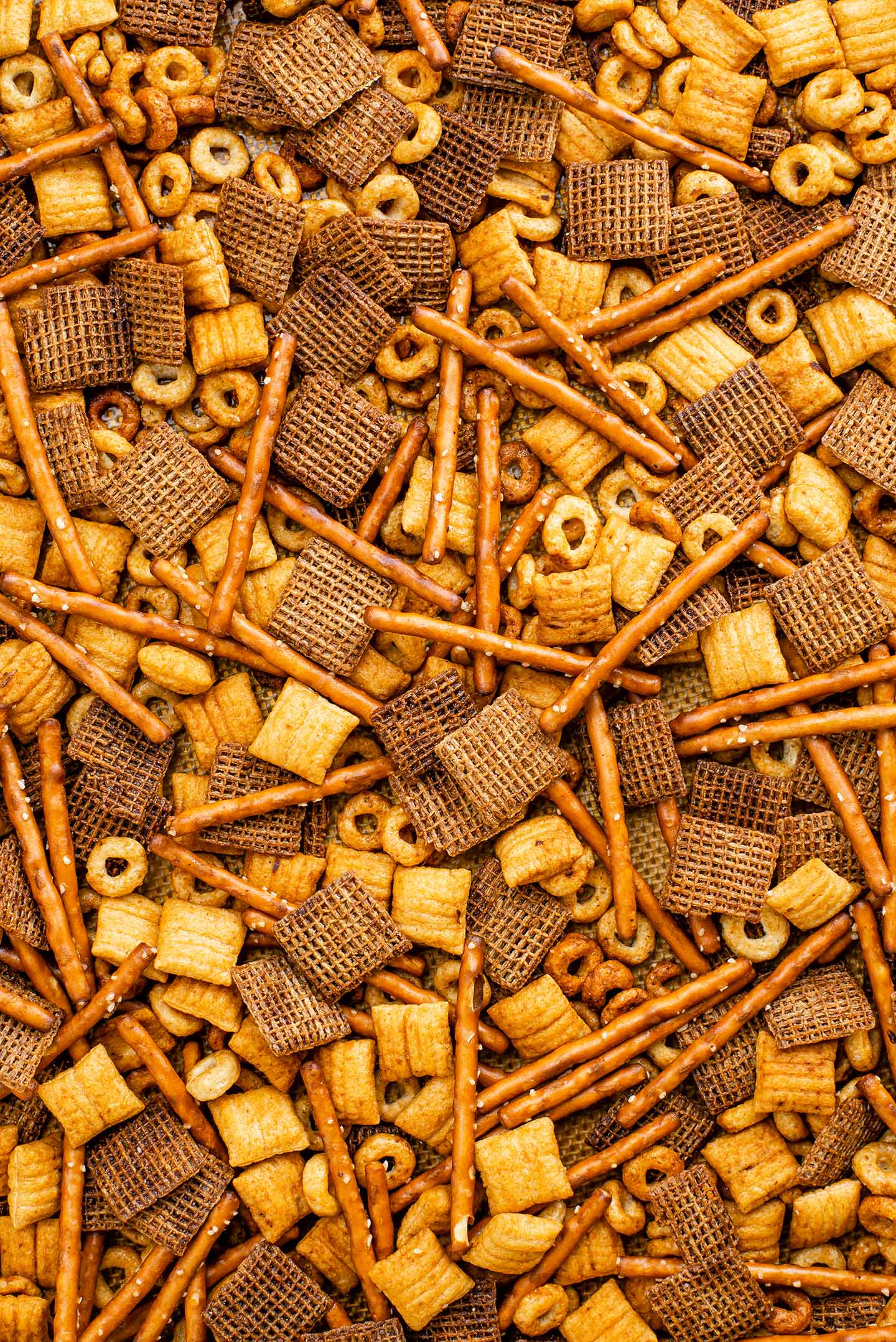 Top down view of easy vegan party mix filling the frame. The golden party mix fills a baking tray after being removed from the oven.