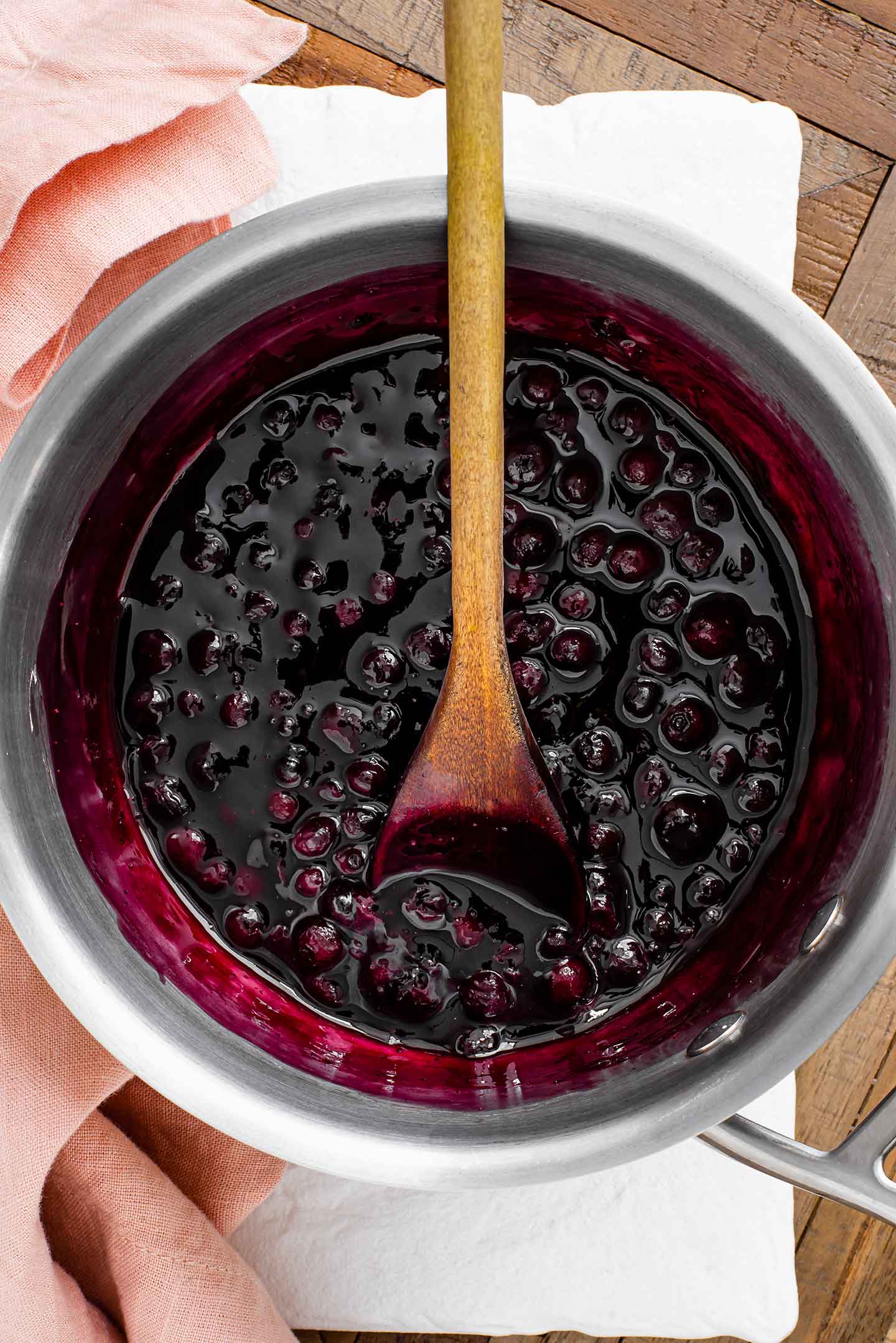 Top down view of a thickened warm blueberry sauce in a small pot.