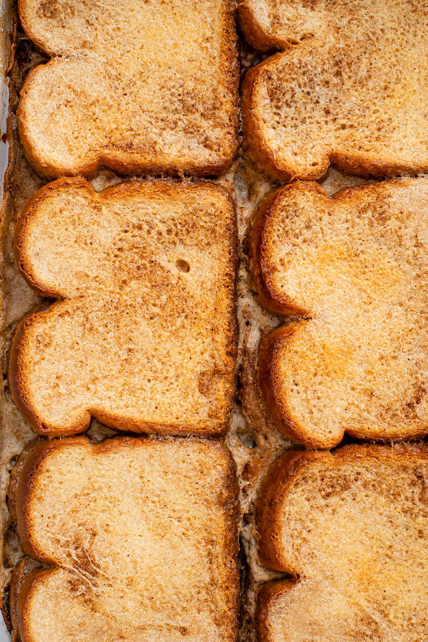 Top down view of a casserole dish full of golden slices of baked french toast.