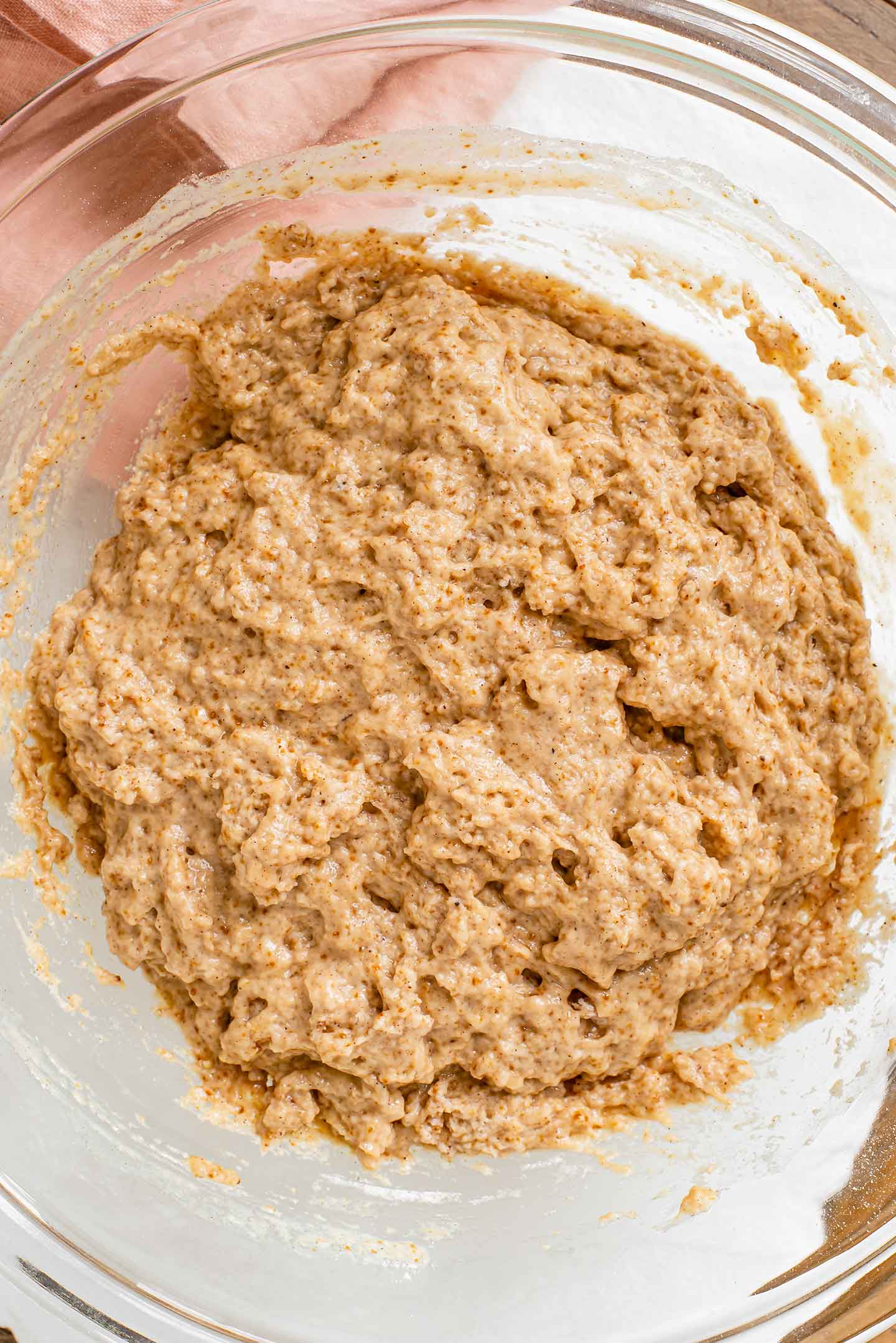 Top down view of the doughnut batter in a glass bowl. The light brown batter is fluffy and moist.