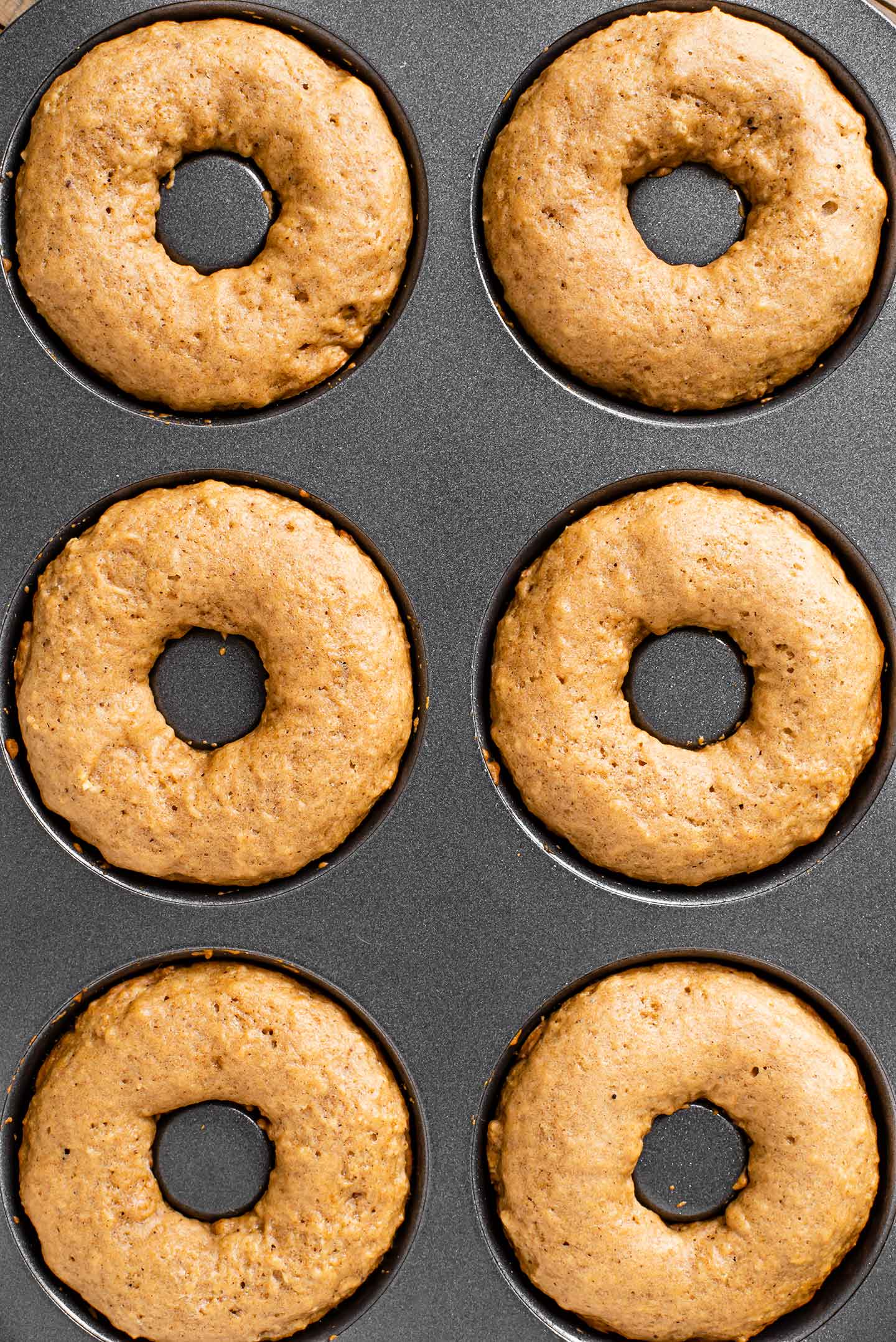 Top down view of the doughnuts puffed up in the tin after baking.