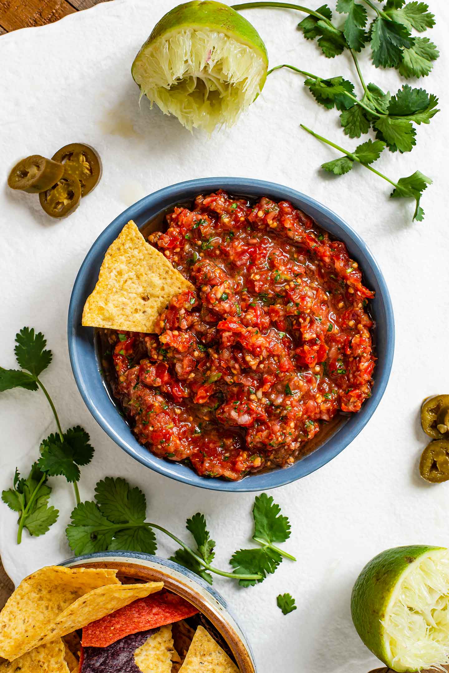 Top down view of easy grape tomato salsa in a shallow dish with a tortilla chip placed in the salsa.