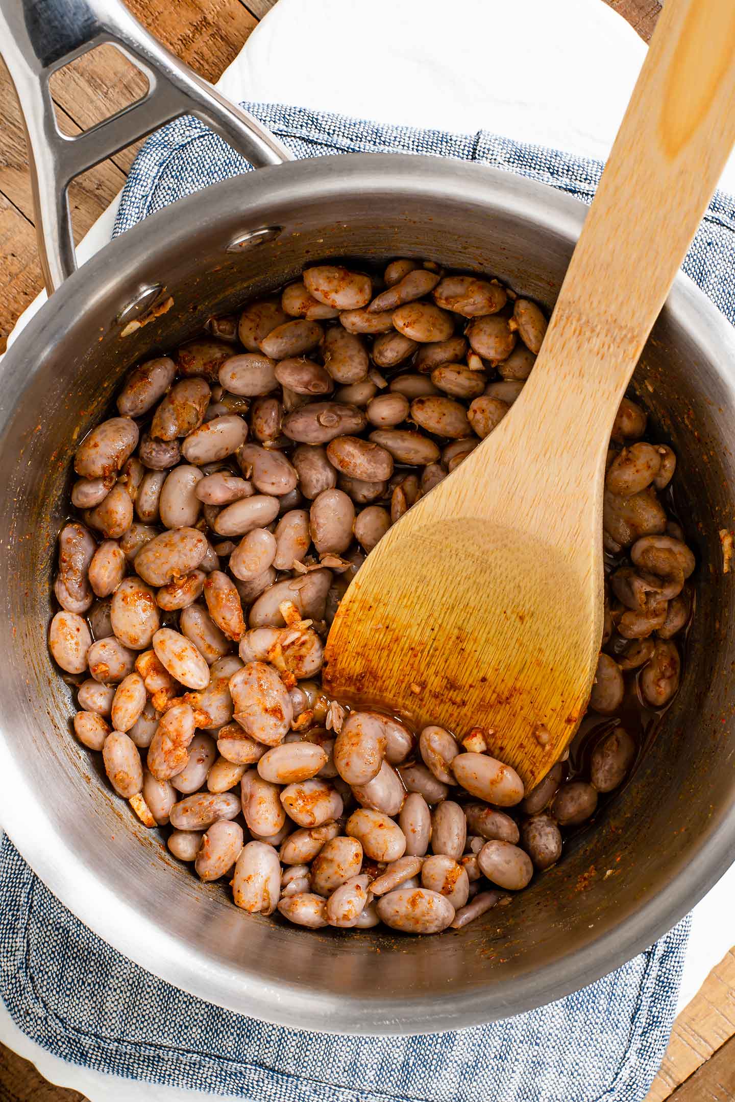 Top down view of seasoned pinto beans cooking in a pot with some broth.
