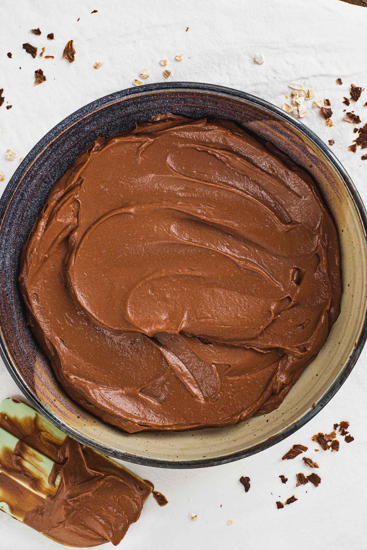 Top down view of the thick chocolate avocado mousse spread across the bottom of a shallow serving bowl. The base layer of the dessert.
