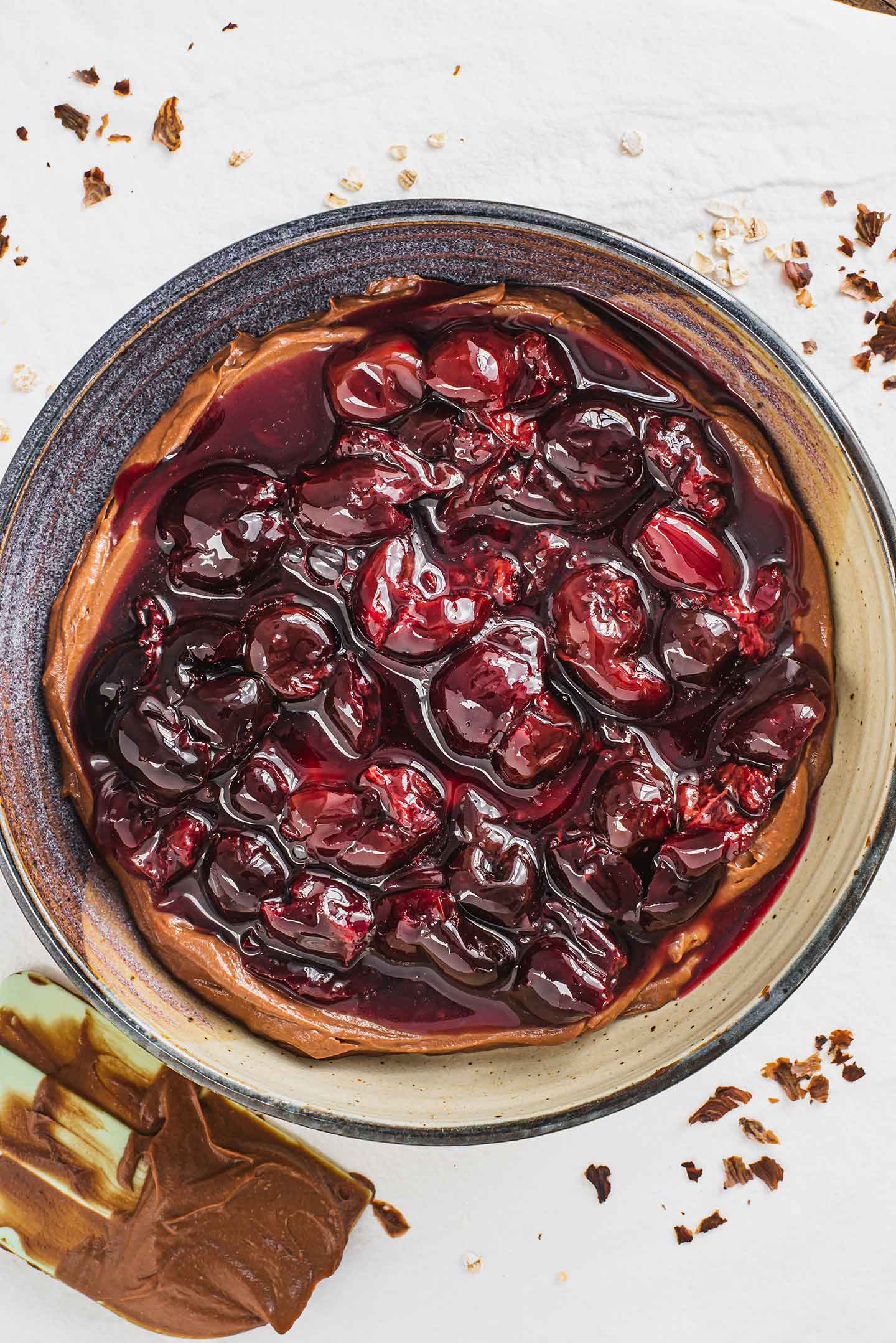 Top down view of a cherry sauce poured over a chocolate mousse in a shallow serving dish. The second layer of a decadent vegan dessert.