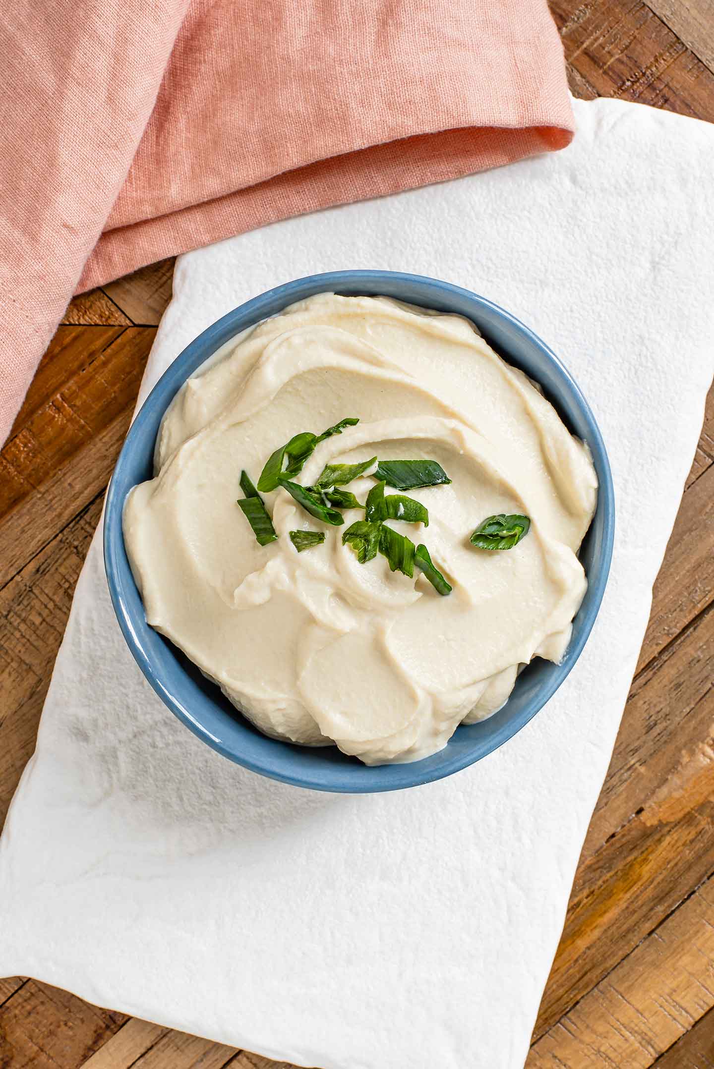 Top down view of a creamy tofu sour cream and onion dip in a bowl topped with sliced green onion.