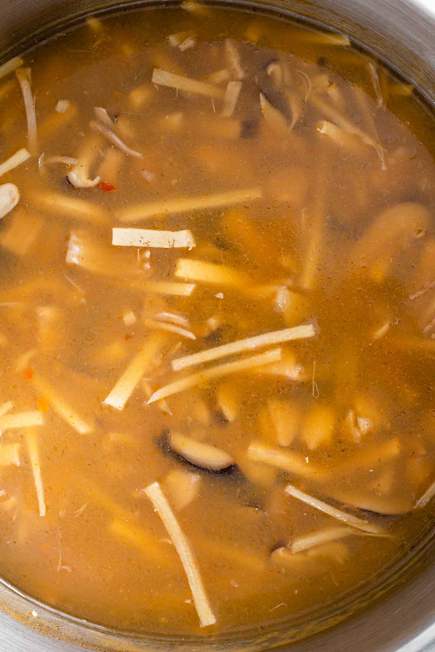 Top down view of vegan hot and sour soup in a large pot.