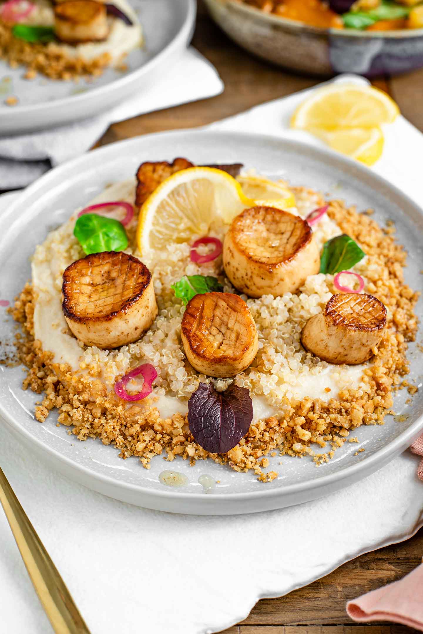 Side view of a plate spread with white parsnip puree, bordered by crumbled candied walnuts and topped with succulent and browned mushroom "scallops".