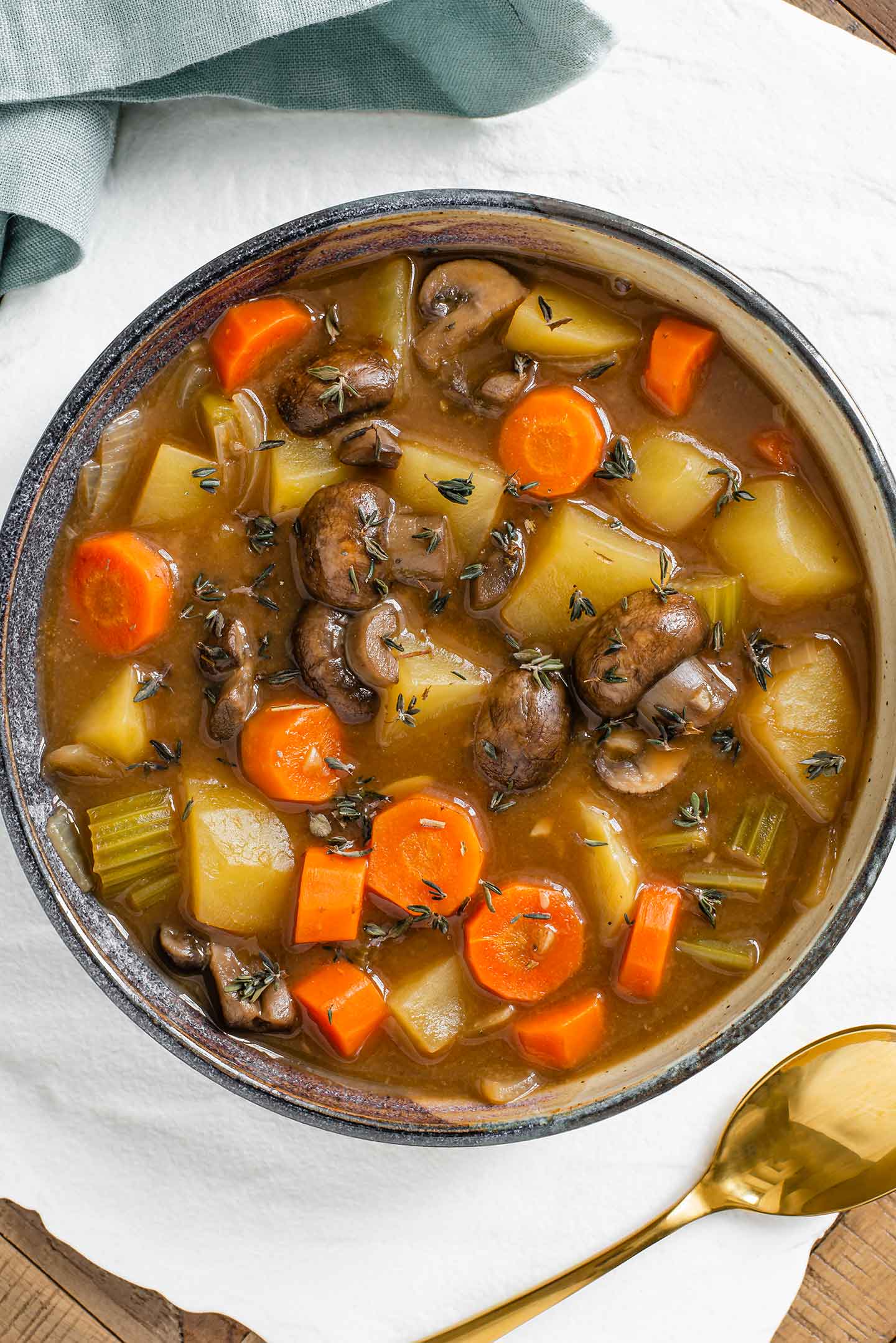 Top down view of a shallow bowl filled with thick vegan Irish Guinness stew. Mushrooms, potatoes, carrots, and celery in a thick gravy.
