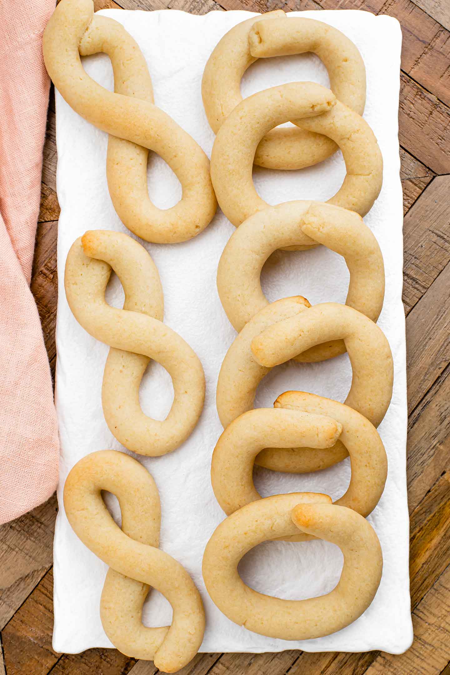 Top down view of Portuguese biscoitos displayed on a white platter. On one side are circular cookies and on the other are cookies formed into a figure eight shape.