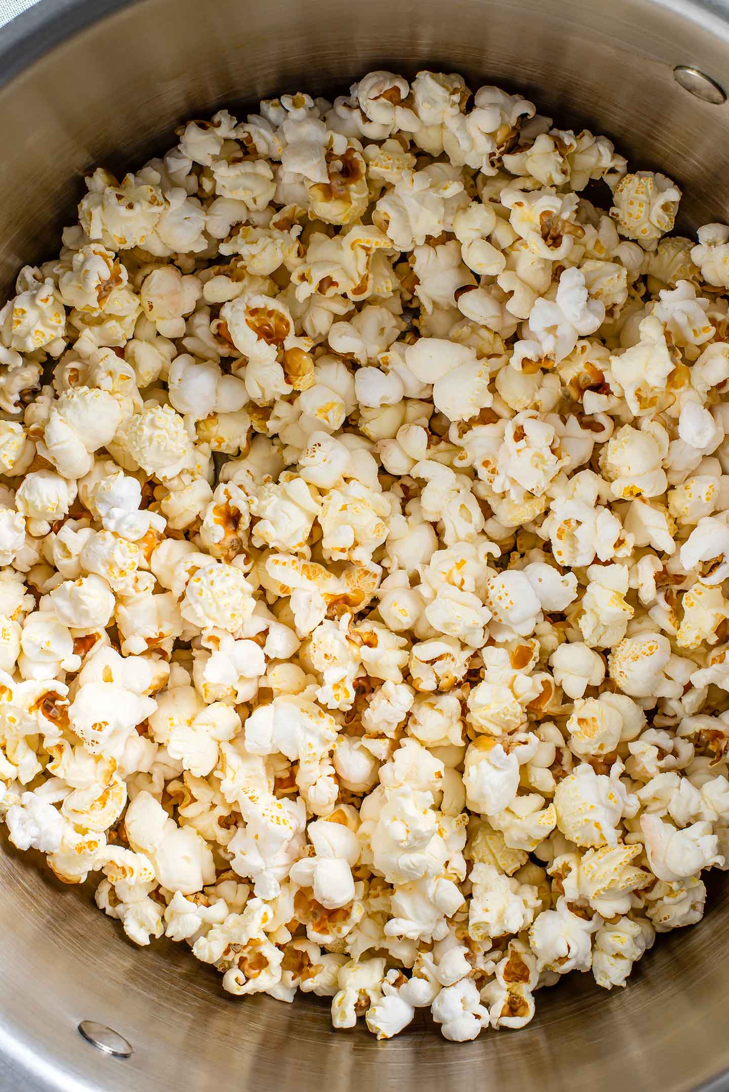 Top down view of fluffy white popcorn in a large steel pot.