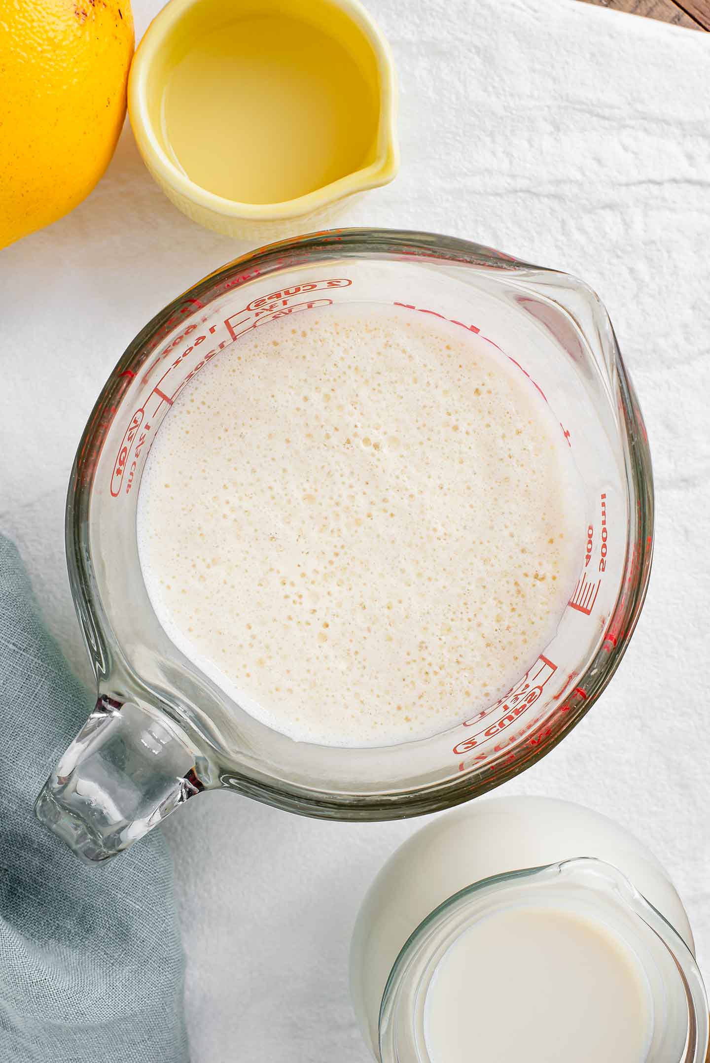 Top down view of homemade vegan buttermilk. Soy milk and lemon juice are combined in a measuring cup to create a thick and soured milk with noticeable clumps.
