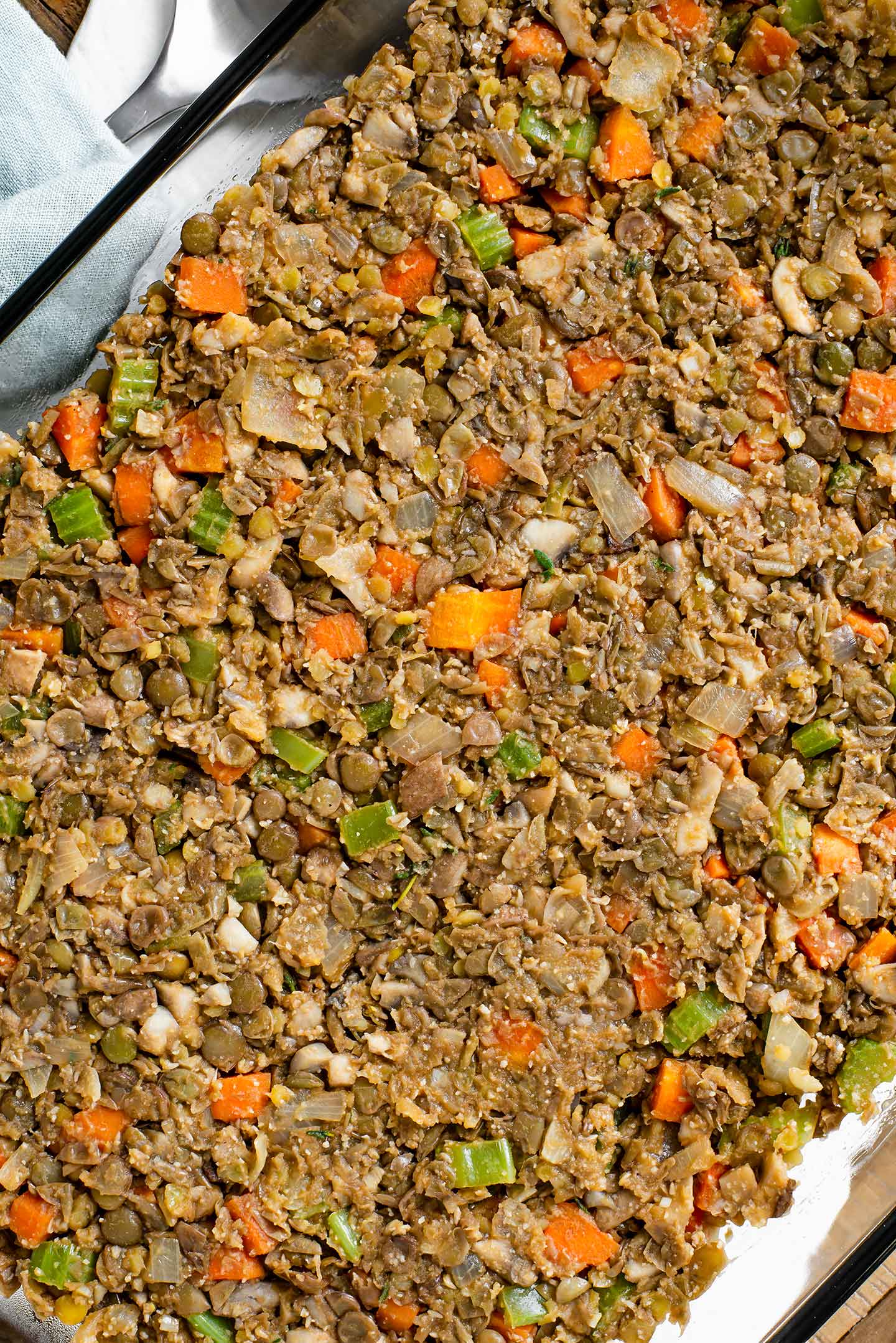 Top down view of the base of the pie in a glass serving dish. Lentils, celery, carrots, and mushrooms are held together with seasonings and almond flour.